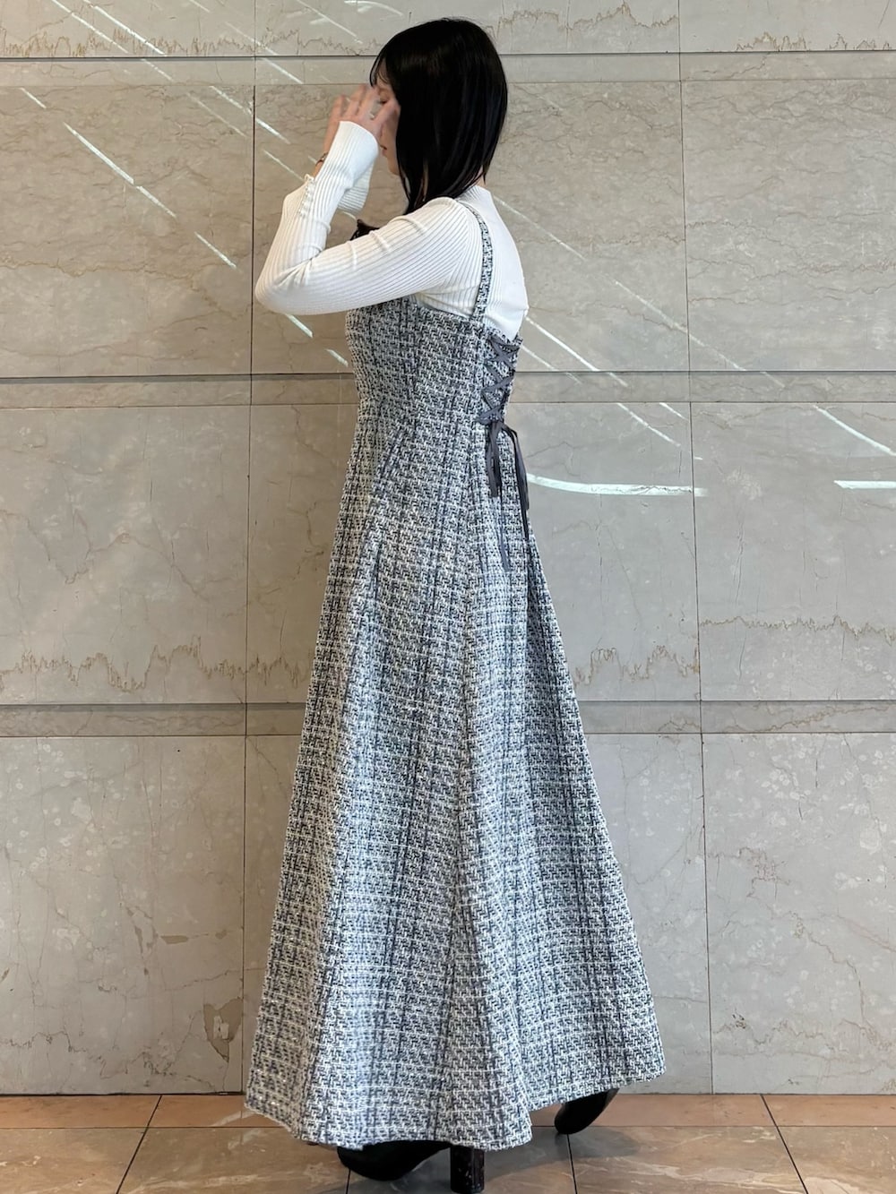 ブラック系のワンピース、ブラック系のブーツ、ホワイト系のニット/セーターを着用したレディースの冬コーディネートの2枚目の写真