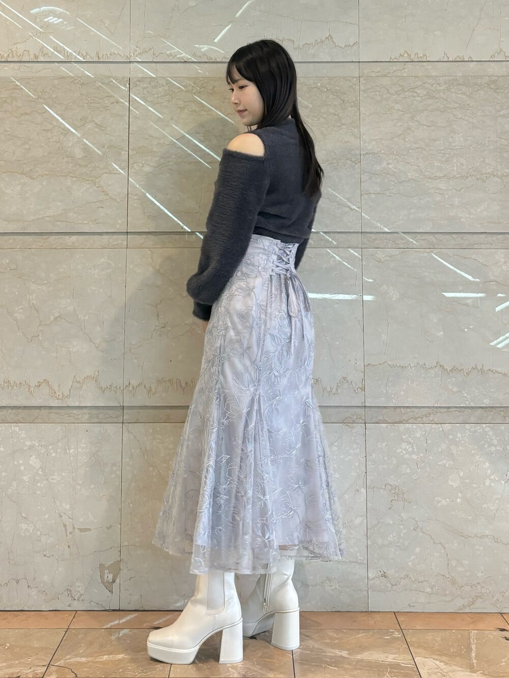 ブルー系のスカート、ホワイト系のブーツ、グレー系のニット/セーターを着用したレディースの秋コーディネートの2枚目の写真