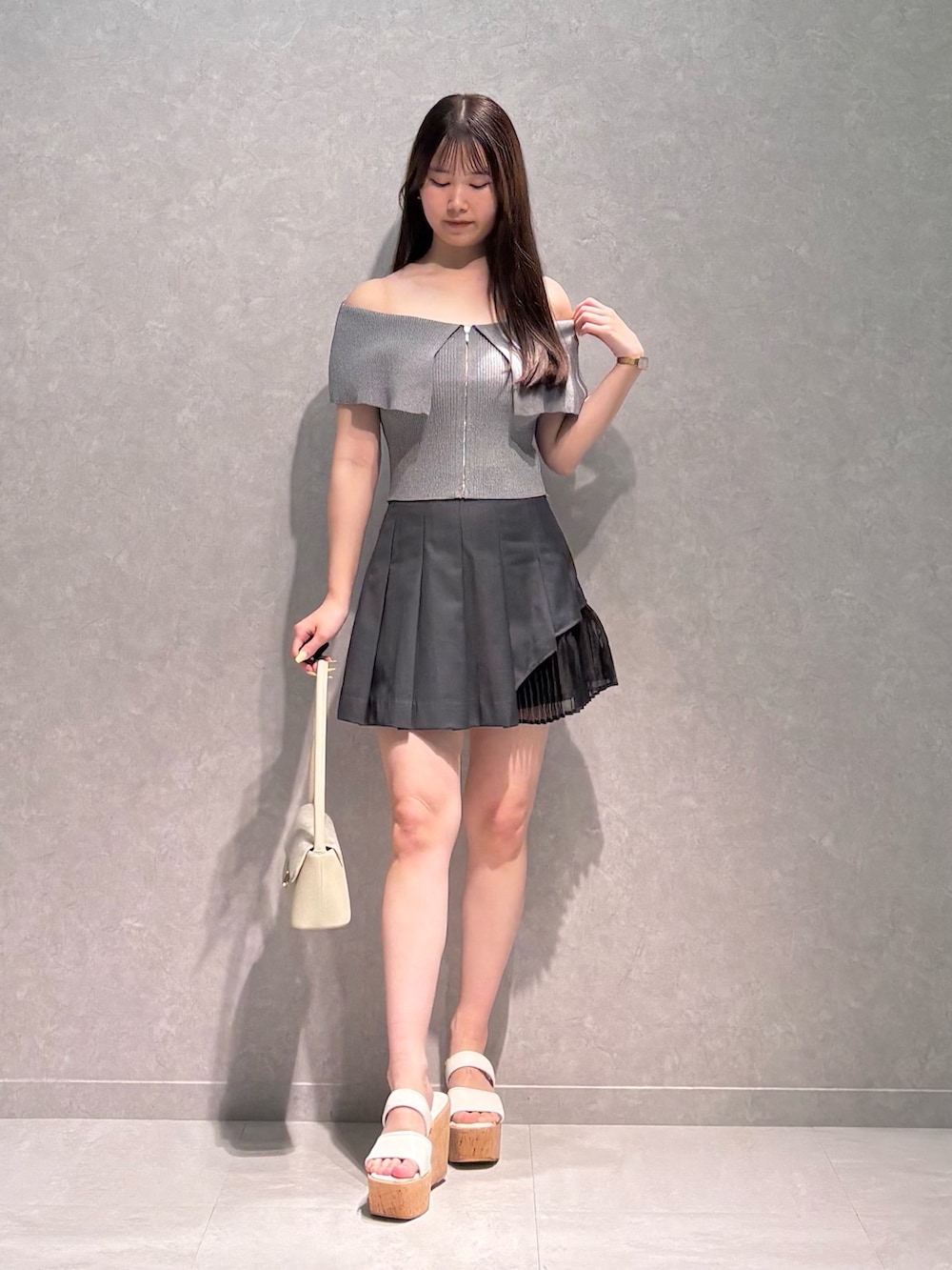 グレー系のスカート、グレー系のニット/セーター、ホワイト系のハンドバッグを着用したレディースの夏コーディネートの3枚目の写真