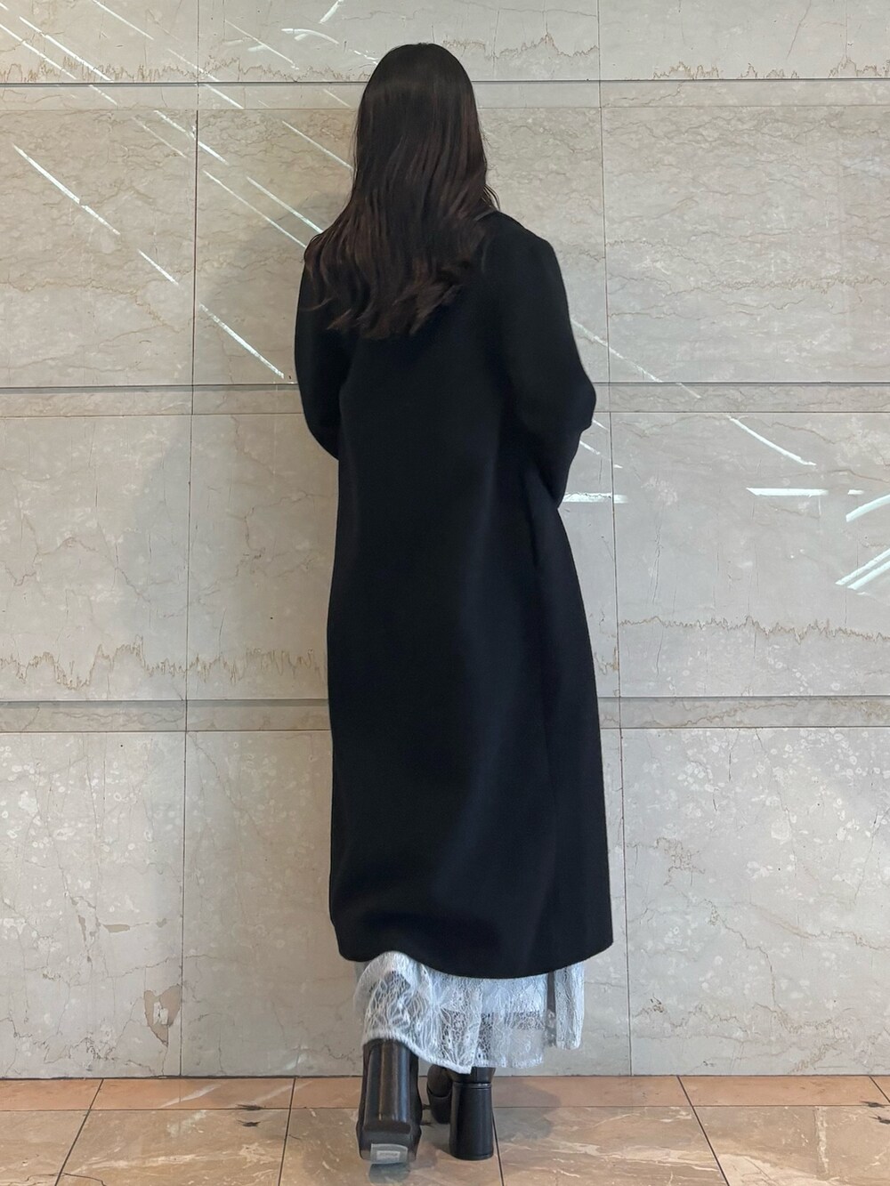 ブルー系のスカート、ブラック系のブーツ、ホワイト系のニット/セーターを着用したレディースの冬コーディネートの4枚目の写真