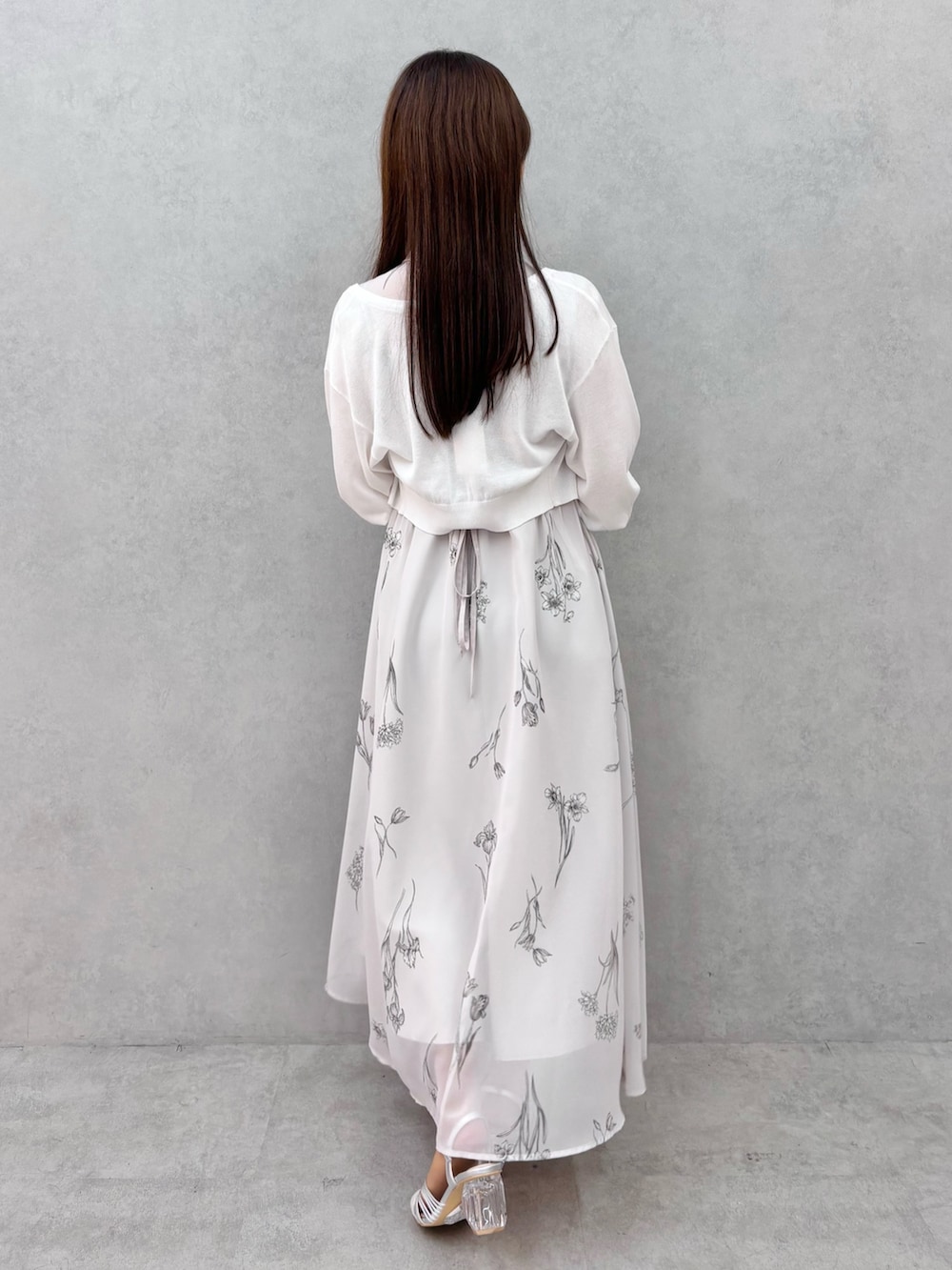 グレー系のワンピース、シルバー系のサンダル、ホワイト系のカーディガン/ボレロを着用したレディースの春コーディネートの4枚目の写真