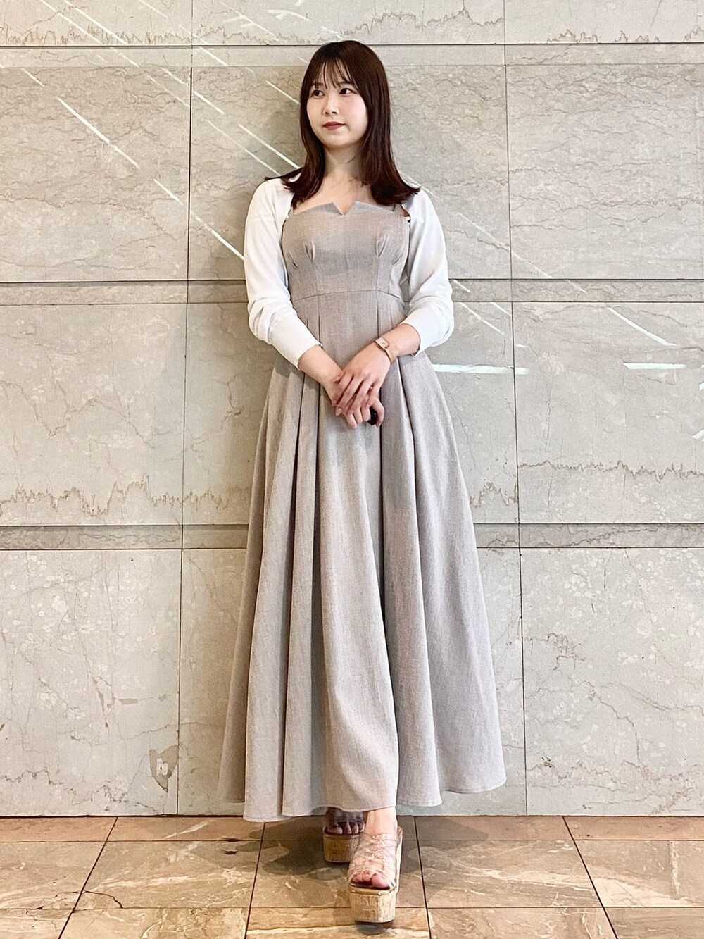 ベージュ系のワンピース、ホワイト系のカーディガン/ボレロ、その他のサンダルを着用したレディースの春コーディネートの2枚目の写真