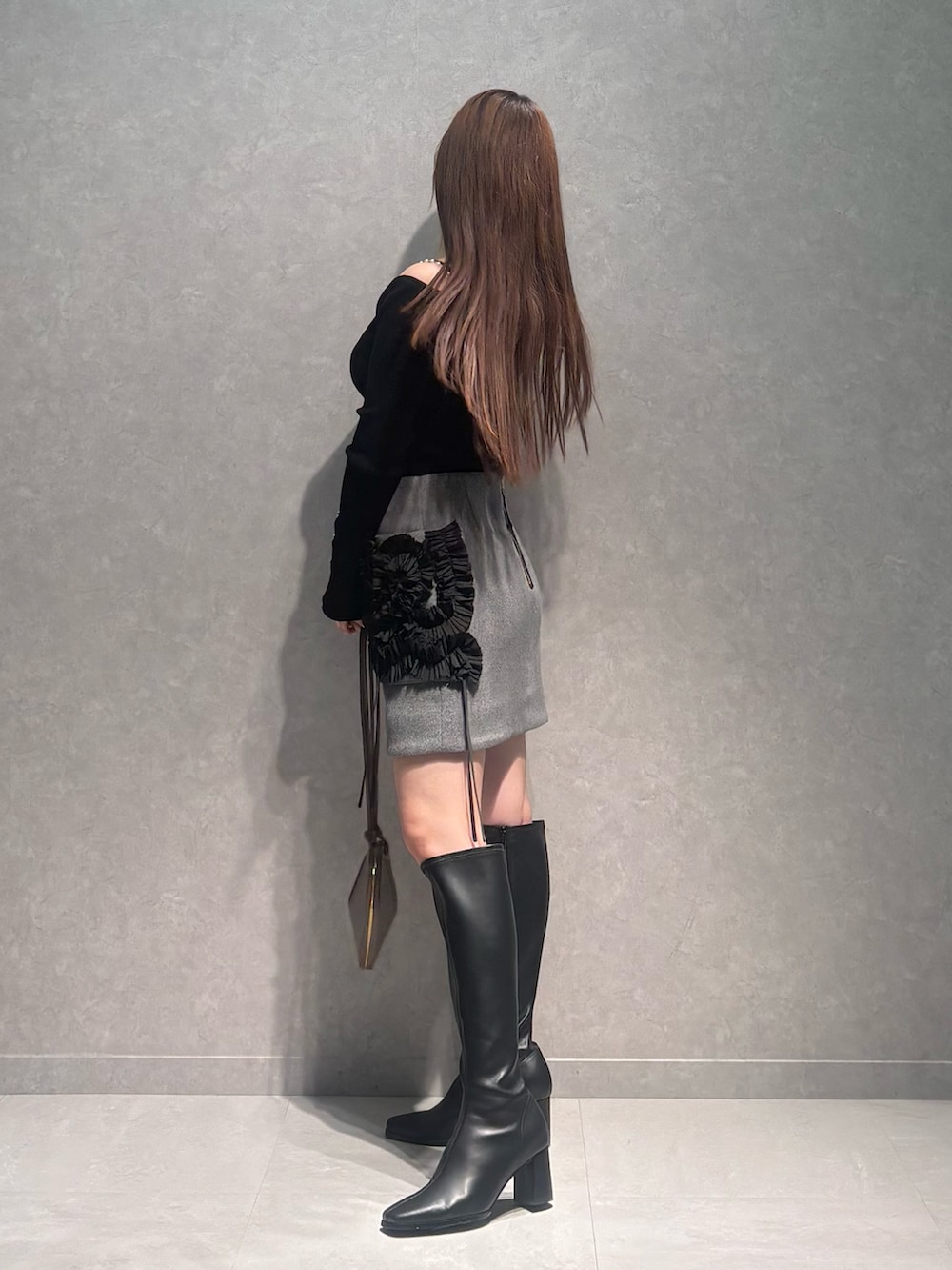 グレー系のスカート、ベージュ系のショルダーバッグ、ブラック系のニット/セーターを着用したレディースの冬コーディネートの4枚目の写真