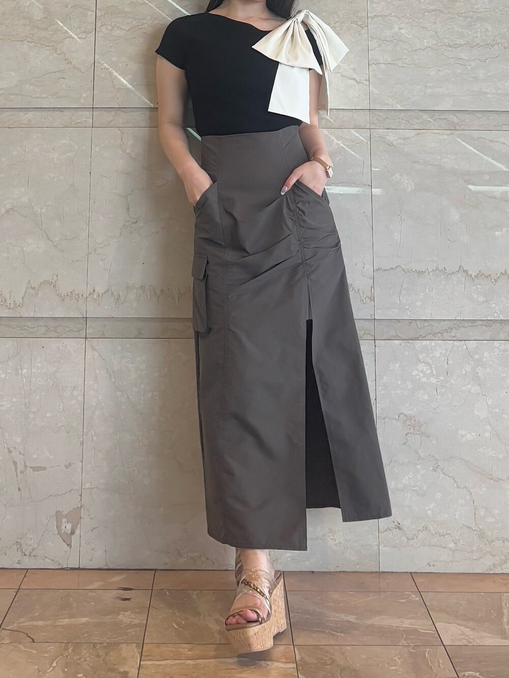 ブラウン系のスカート、ブラウン系のサンダル、ブラック系のニット/セーターを着用したレディースの夏コーディネートの2枚目の写真