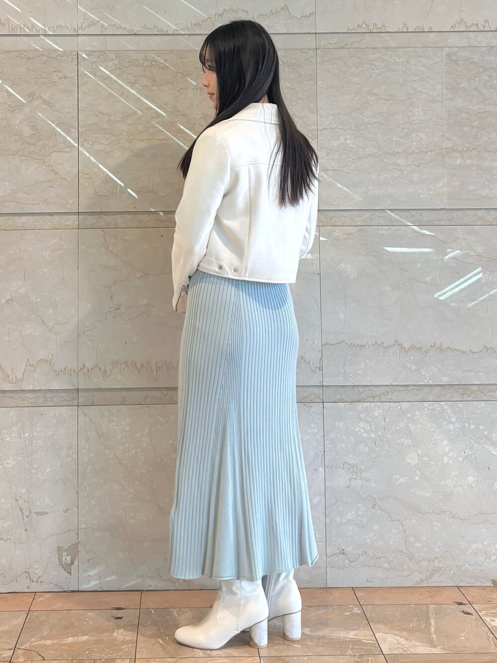 ブルー系のワンピース、ホワイト系のブーツ、ホワイト系のライダースジャケットを着用したレディースの冬コーディネートの3枚目の写真