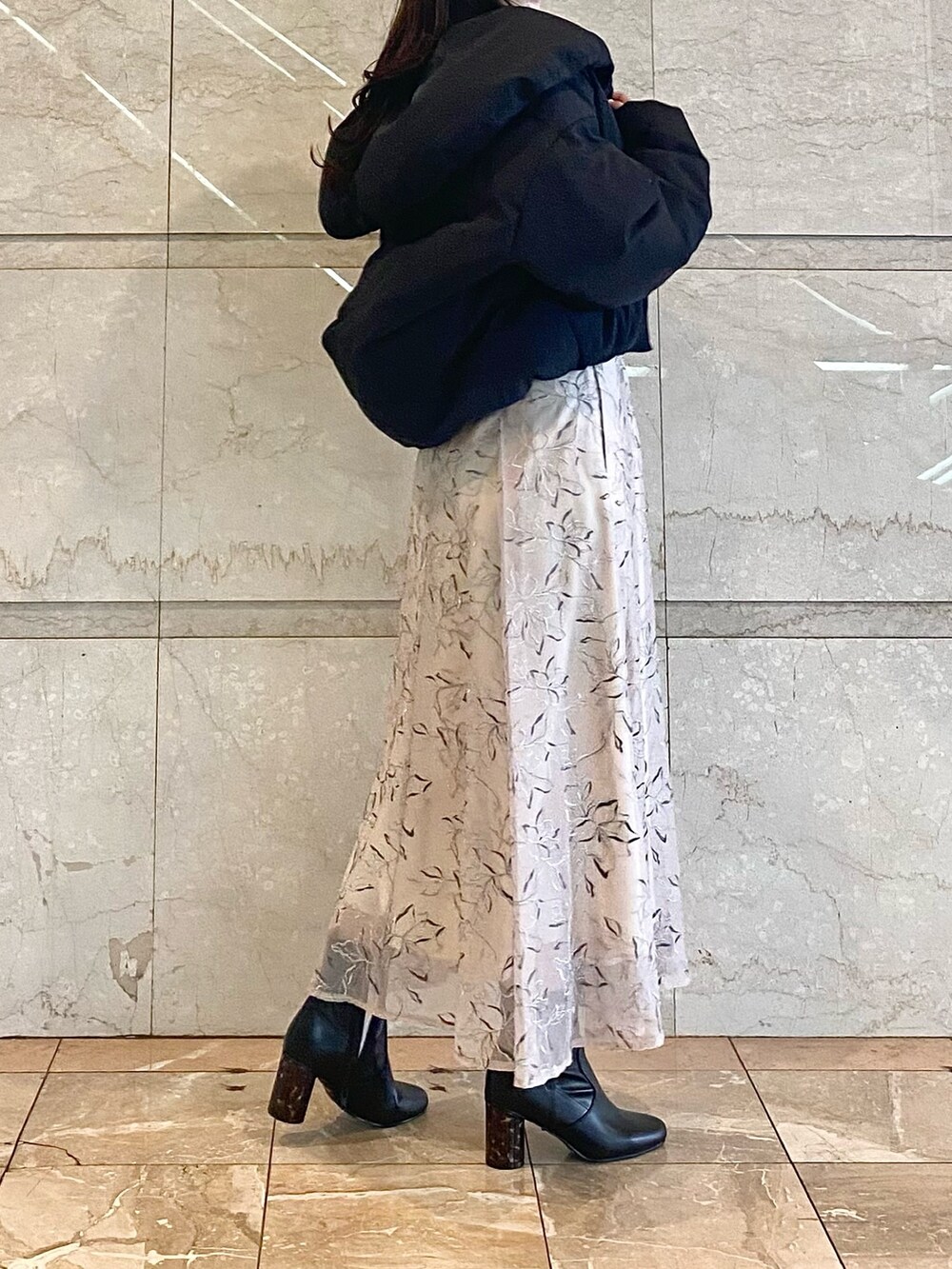 ベージュ系のスカート、グレー系のニット/セーター、ブラック系のダウンジャケット/コートを着用したレディースの冬コーディネートの4枚目の写真