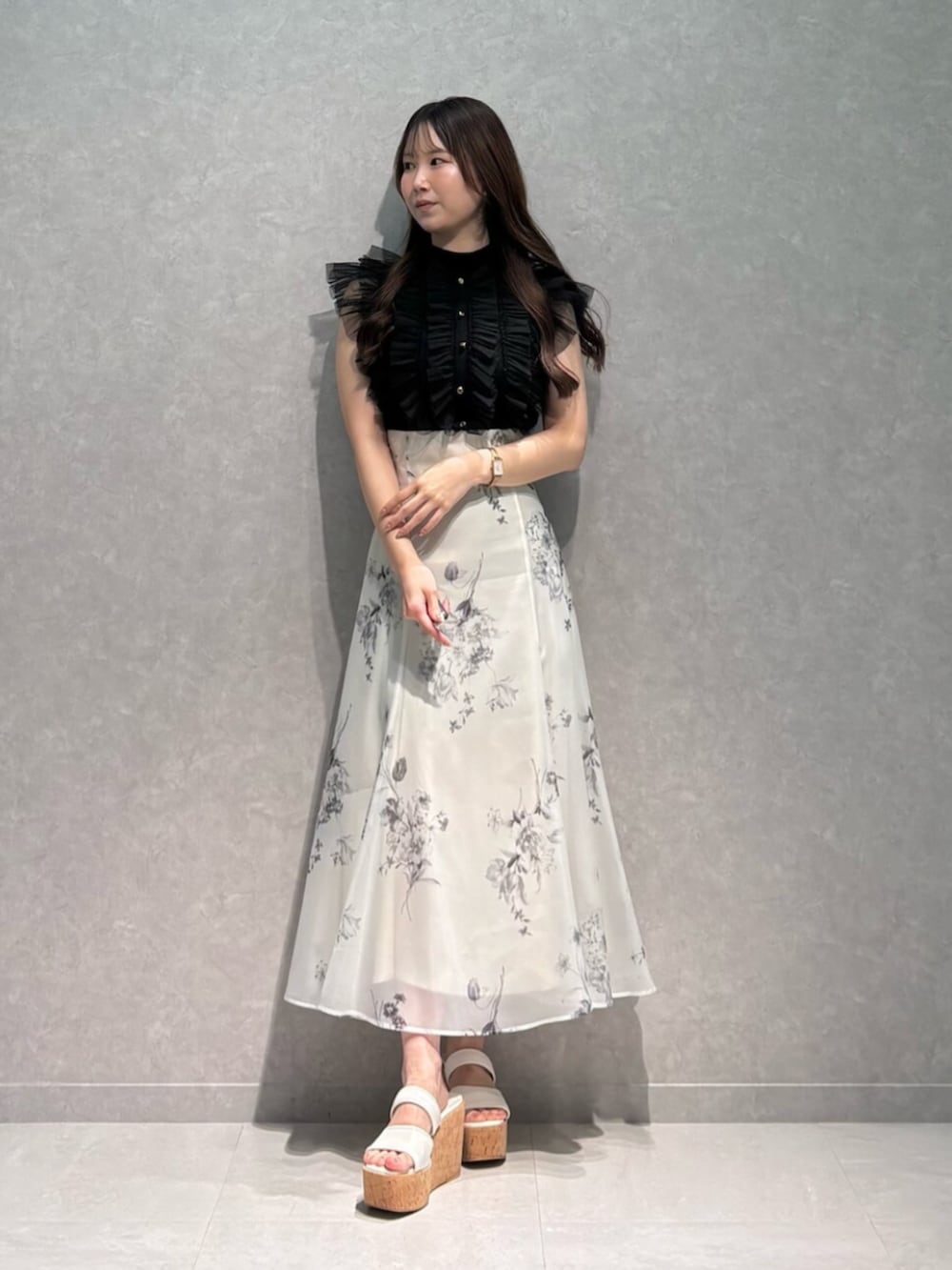 ホワイト系のサンダル、ホワイト系のスカート、ブラック系のニット/セーターを着用したレディースの夏コーディネートの2枚目の写真