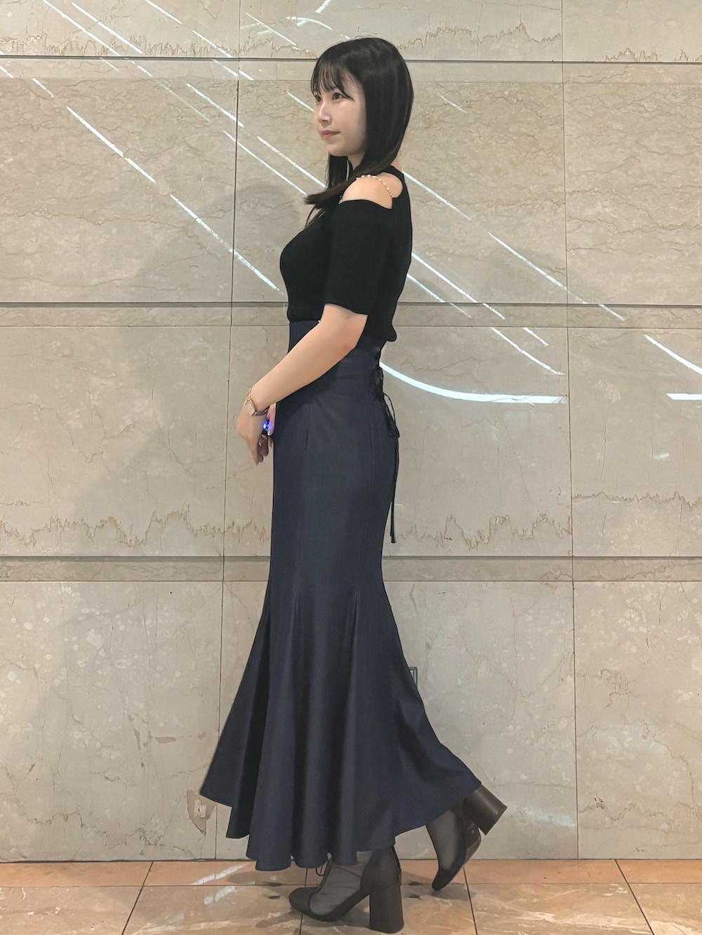 ブルー系のスカート、ブラウン系のブーツ、ブラック系のニット/セーターを着用したレディースの秋コーディネートの2枚目の写真