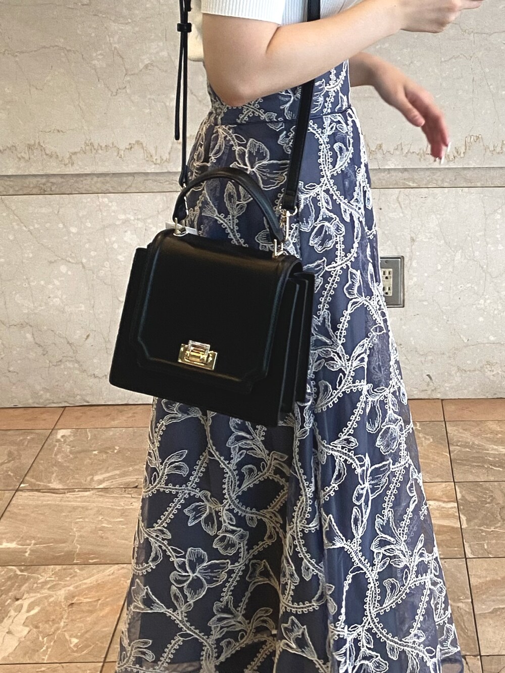 グレー系のスカート、ホワイト系のニット/セーター、ブラック系のブーツを着用したレディースの夏コーディネートの5枚目の写真