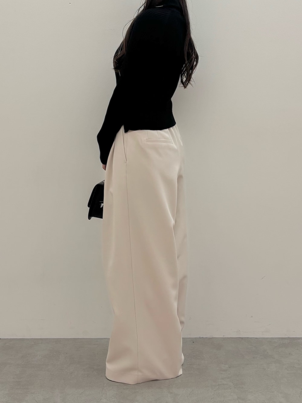 ブラック系のニット/セーター、ブラック系のハンドバッグ、ブラウン系のブーツを着用したレディースの秋コーディネートの3枚目の写真