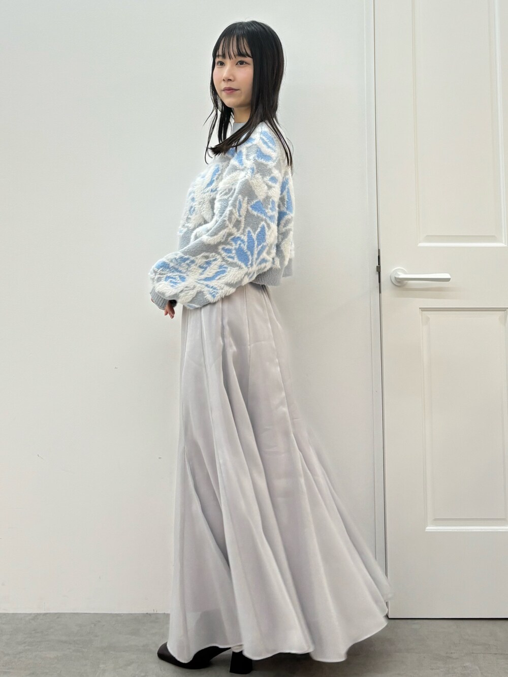 ブルー系のニット/セーター、ブラウン系のブーツ、グレー系のスカートを着用したレディースの秋コーディネートの4枚目の写真