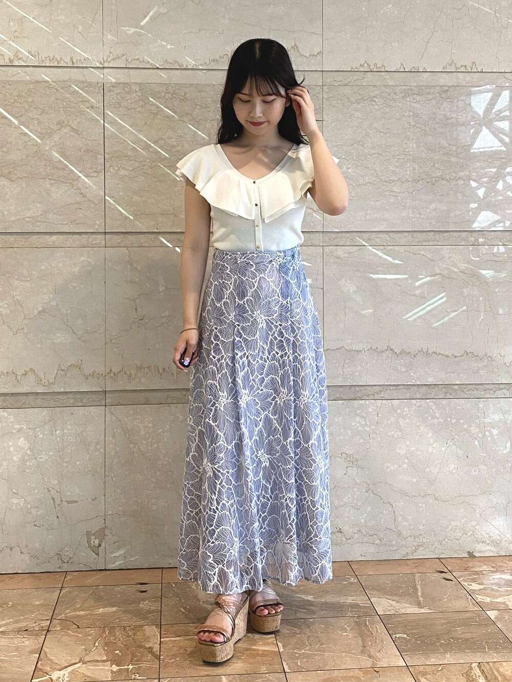 ブルー系のスカート、ホワイト系のニット/セーターを着用したレディースの夏コーディネートの3枚目の写真