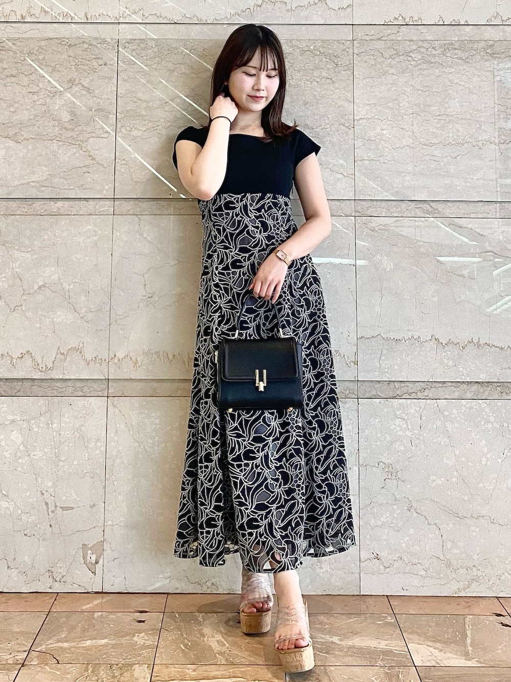 ブラック系のハンドバッグ、その他のサンダル、ブラック系のワンピースを着用したレディースの春コーディネートの3枚目の写真