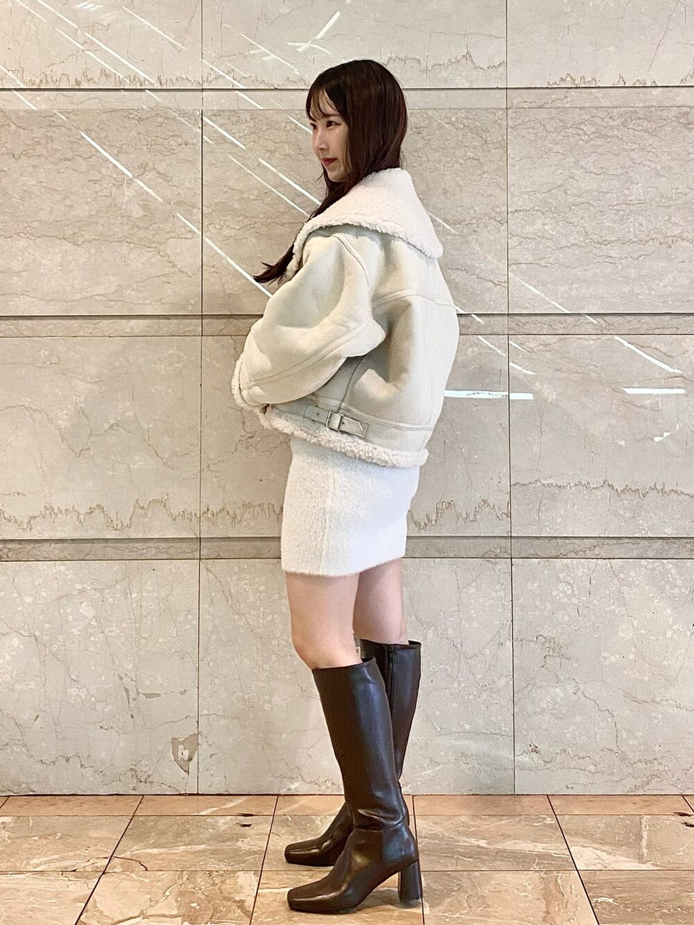 ホワイト系のムートンコート、ホワイト系のワンピース、ブラウン系のブーツを着用したレディースの秋コーディネートの3枚目の写真