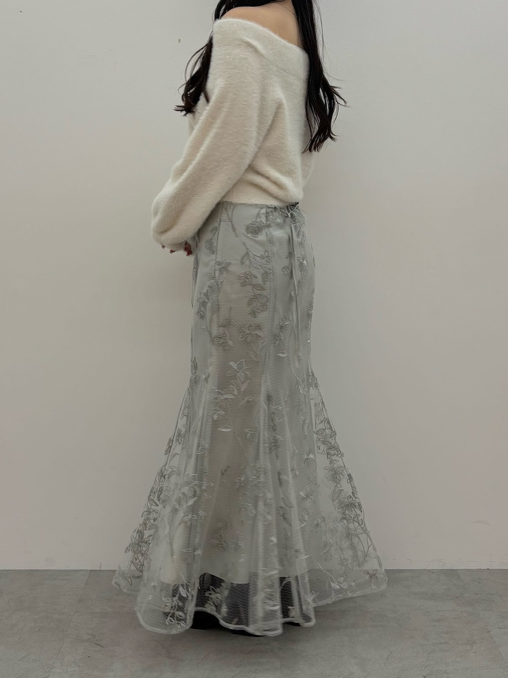 ホワイト系のニット/セーター、ブラウン系のブーツ、グリーン系のスカートを着用したレディースの秋コーディネートの5枚目の写真