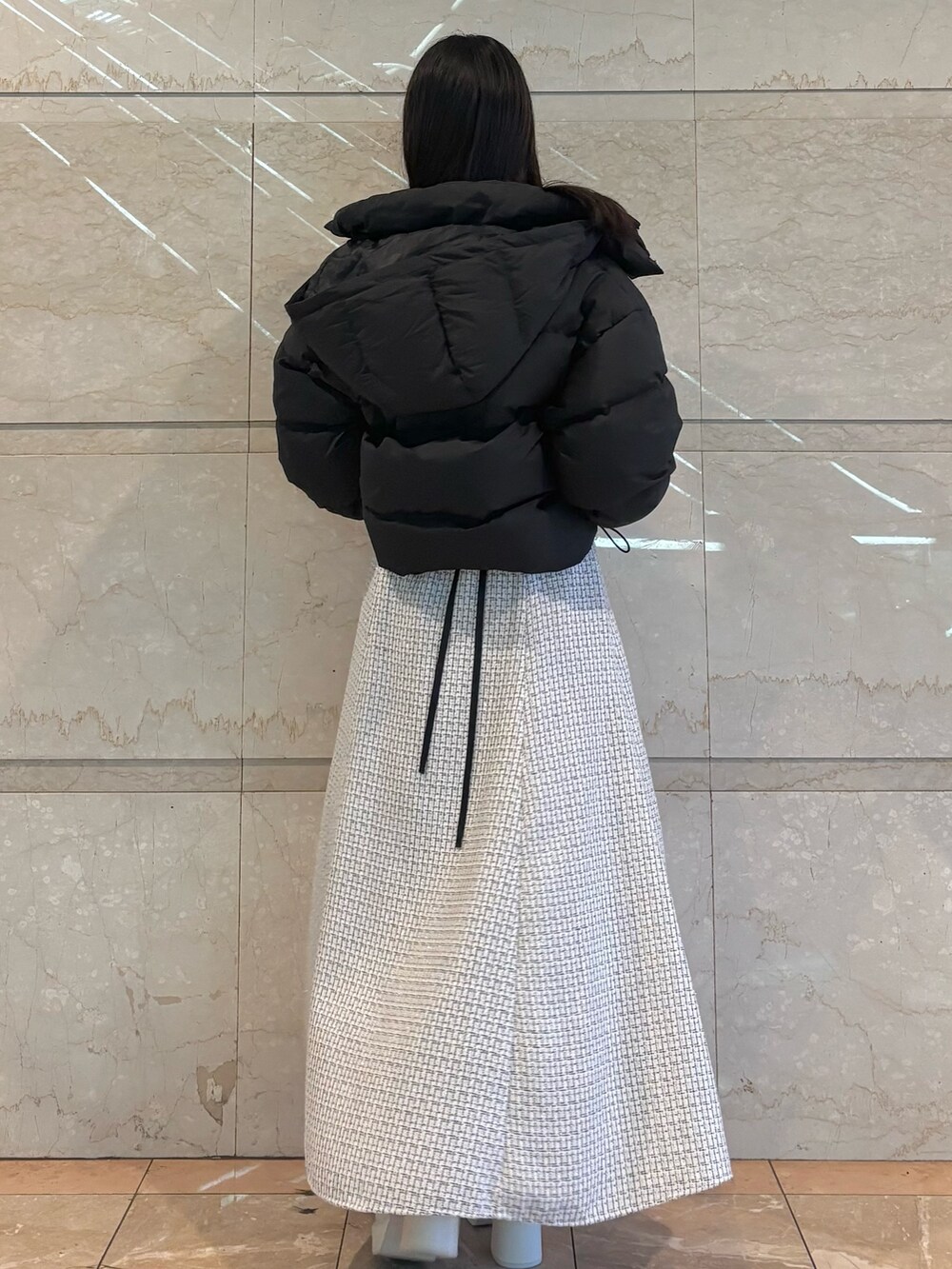 ホワイト系のスカート、ホワイト系のブーツ、ブラック系のダウンジャケット/コートを着用したレディースの冬コーディネートの4枚目の写真