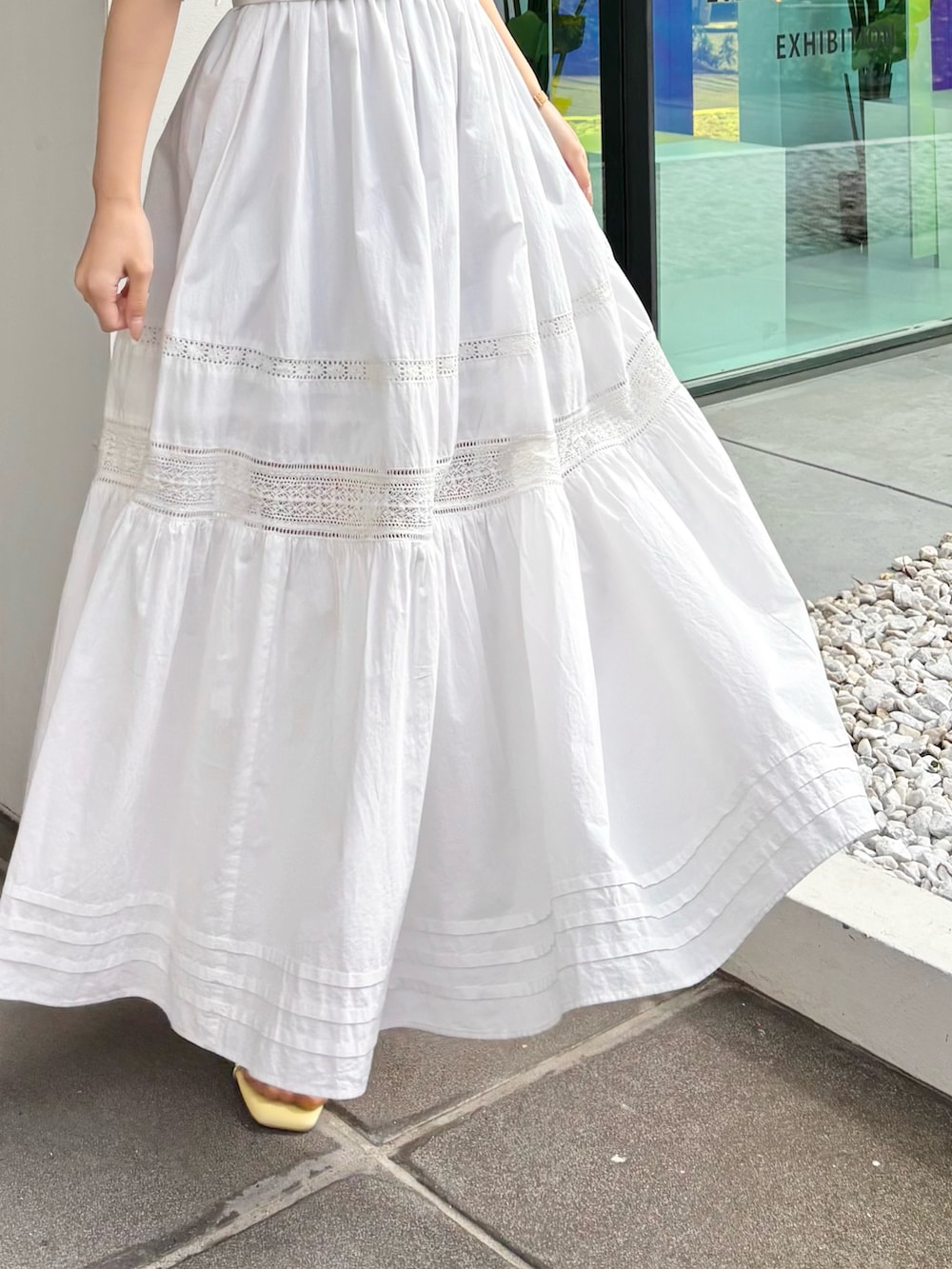 ホワイト系のワンピース、ホワイト系のカーディガン/ボレロ、イエロー系のサンダルを着用したレディースの春コーディネートの3枚目の写真