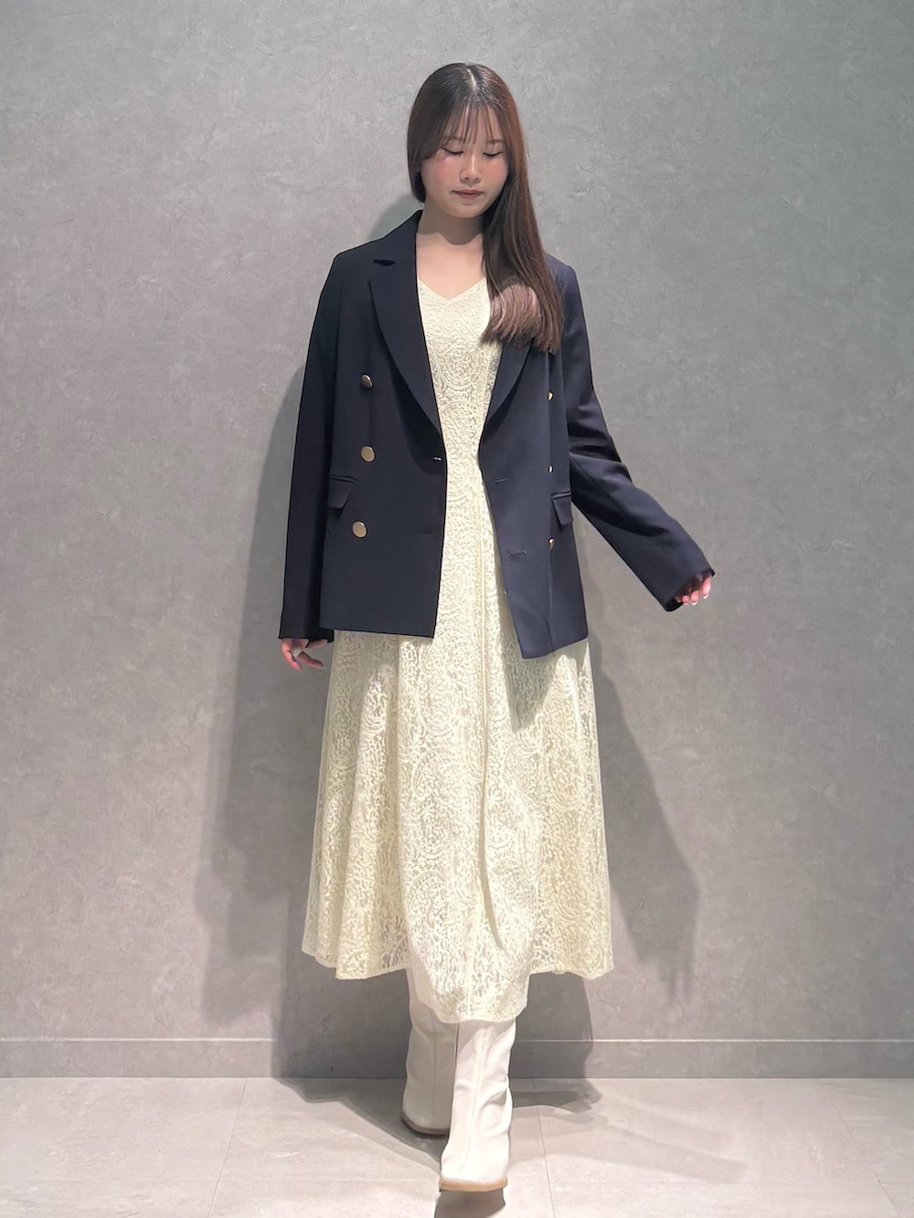 イエロー系のワンピース、ホワイト系のブーツ、ブルー系のテーラードジャケットを着用したレディースの春コーディネートの2枚目の写真