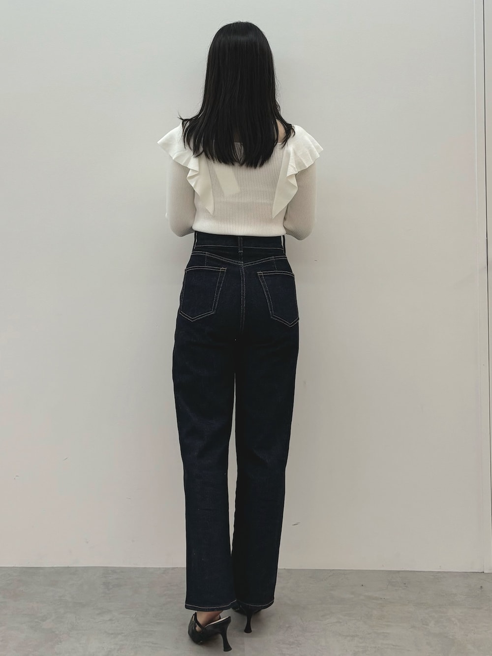 ブルー系のデニムパンツ、ブラック系のパンプス、ホワイト系のニット/セーターを着用したレディースの秋コーディネートの3枚目の写真