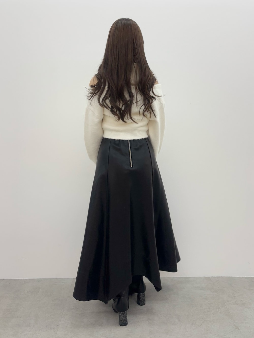 ホワイト系のニット/セーター、ブラック系のスカート、ブラック系のブーツを着用したレディースの冬コーディネートの3枚目の写真