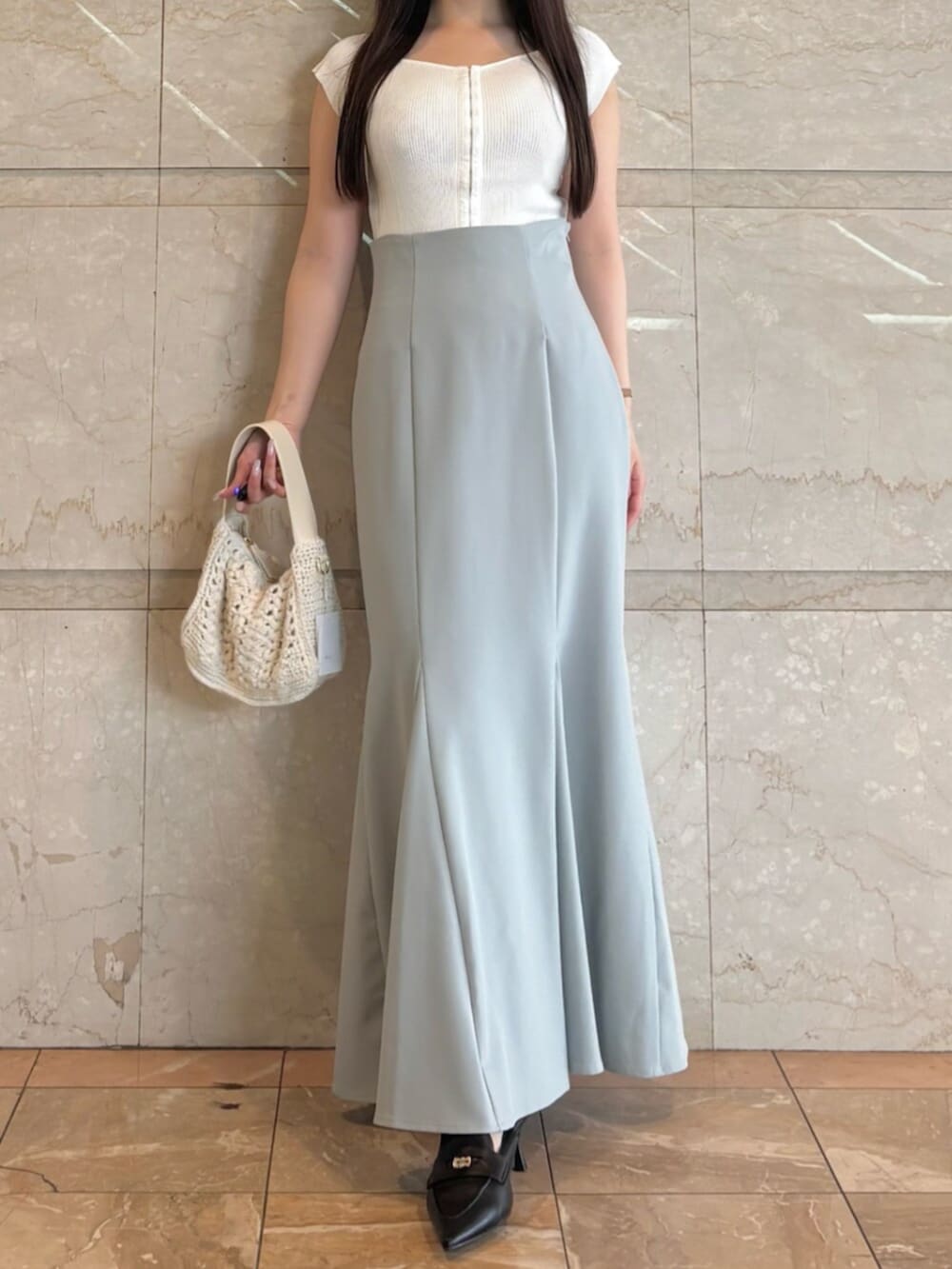 ブラック系のパンプス、ブルー系のスカート、ホワイト系のニット/セーターを着用したレディースの夏コーディネートの2枚目の写真