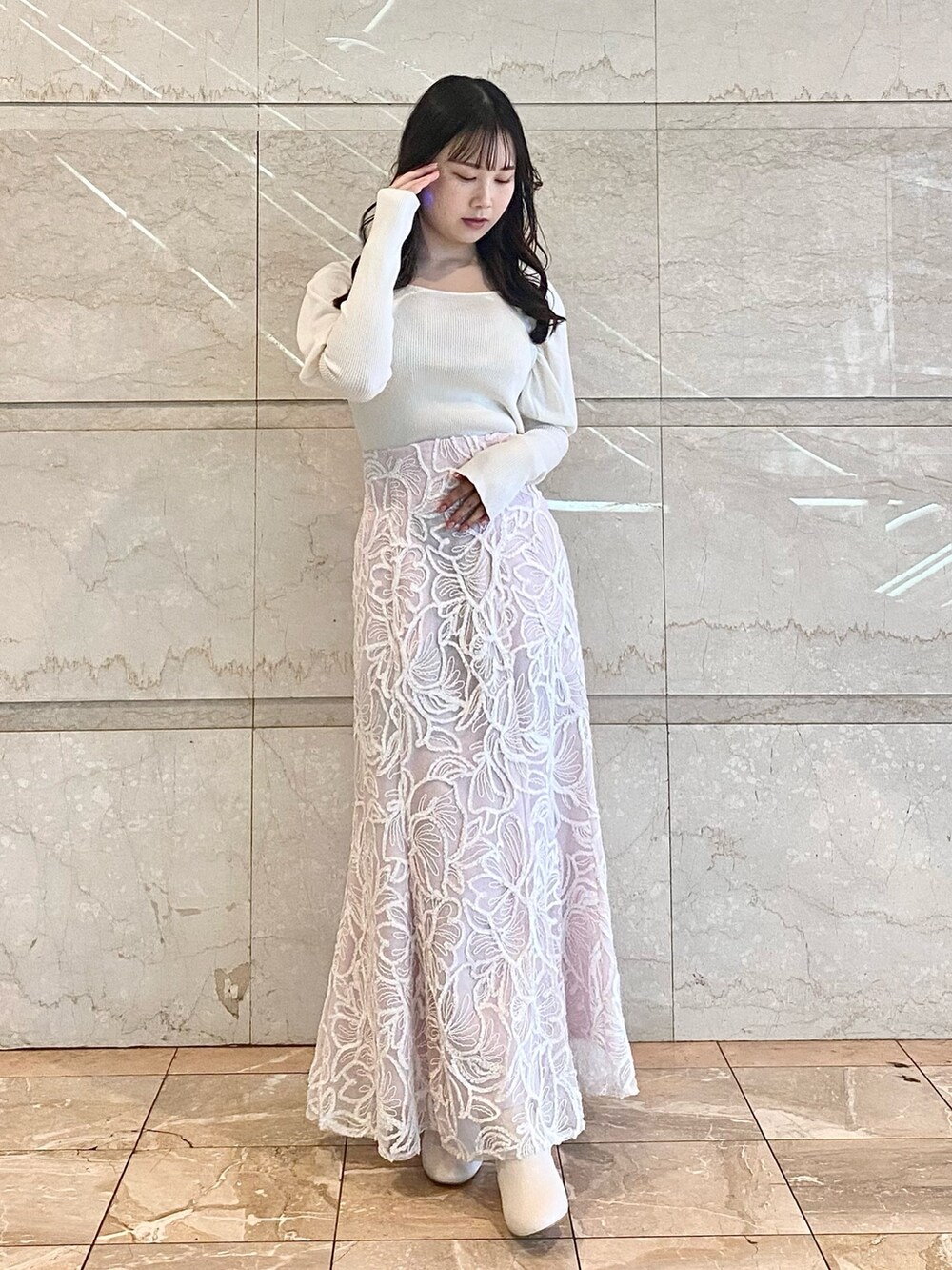 ピンク系のスカート、ホワイト系のブーツ、ホワイト系のニット/セーターを着用したレディースの冬コーディネートの2枚目の写真