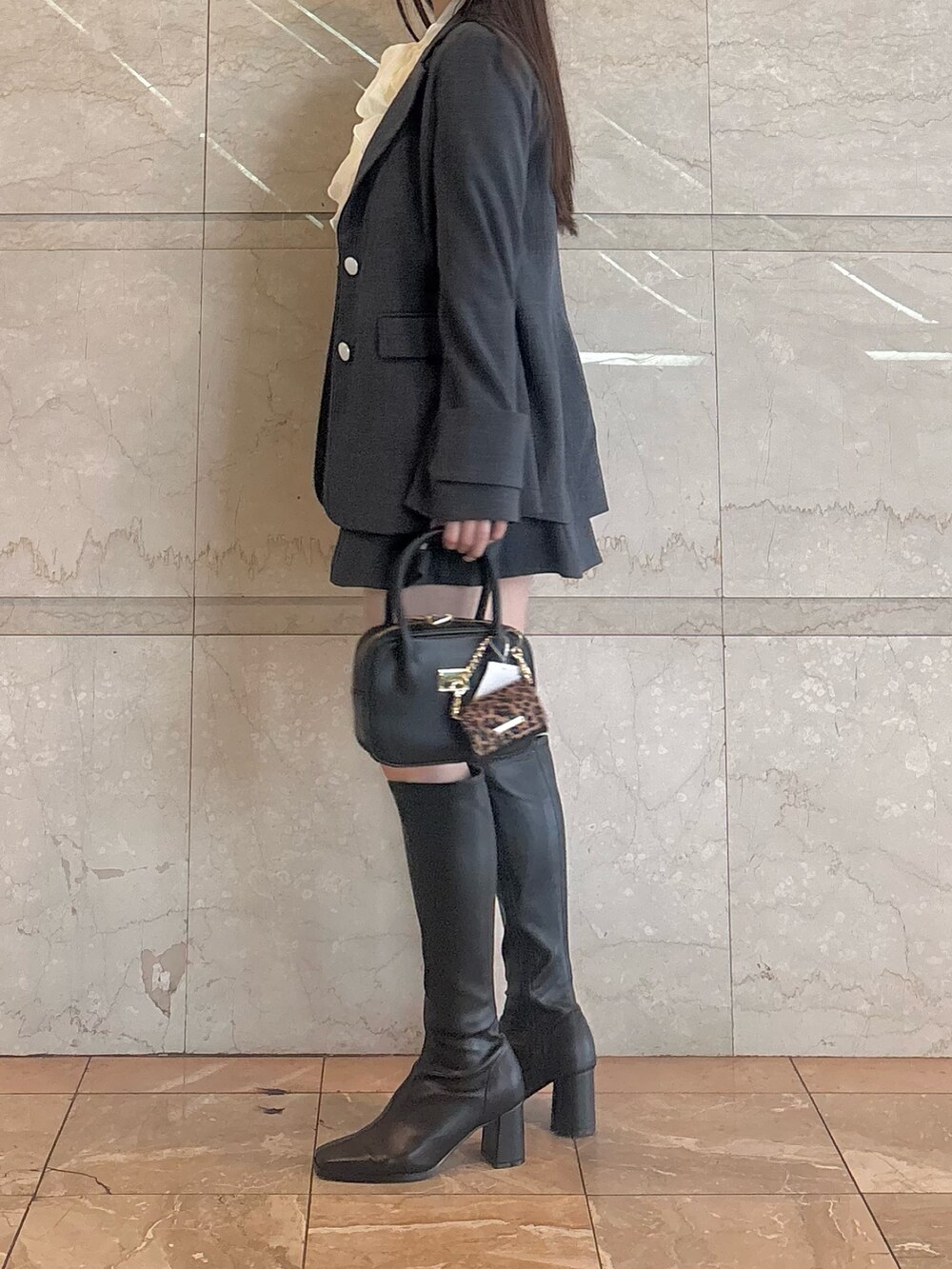 グレー系のスカート、ホワイト系のシャツ/ブラウス、ブラック系のハンドバッグを着用したレディースの秋コーディネートの4枚目の写真