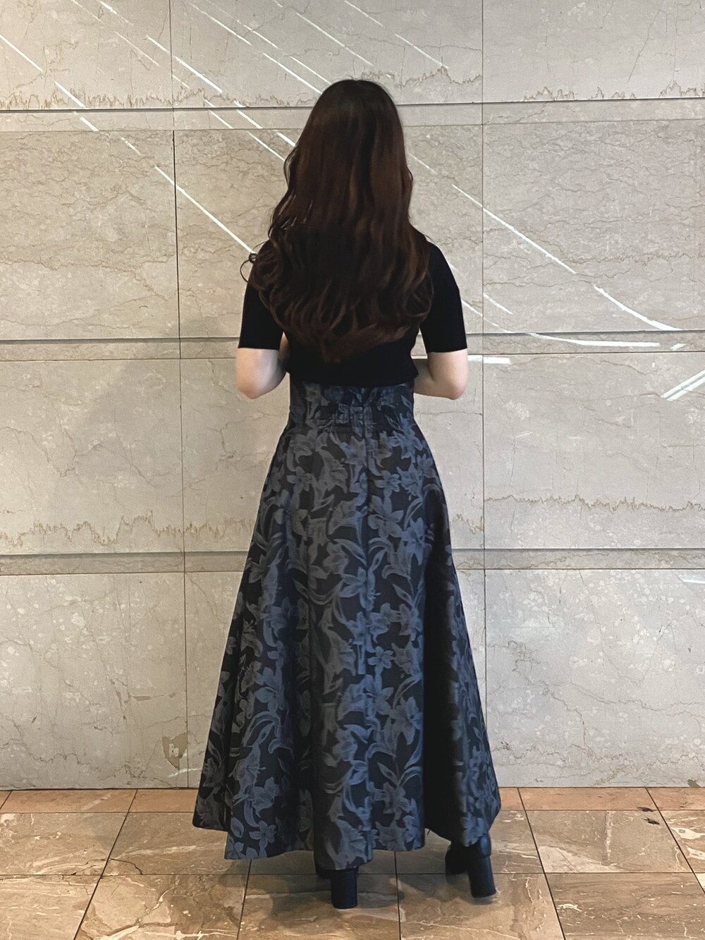 グレー系のスカート、ブラック系のブーツ、ホワイト系のニット/セーターを着用したレディースの秋コーディネートの5枚目の写真