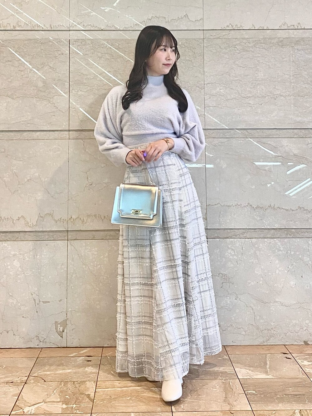 シルバー系のハンドバッグ、ホワイト系のブーツ、パープル系のニット/セーターを着用したレディースの冬コーディネートの5枚目の写真