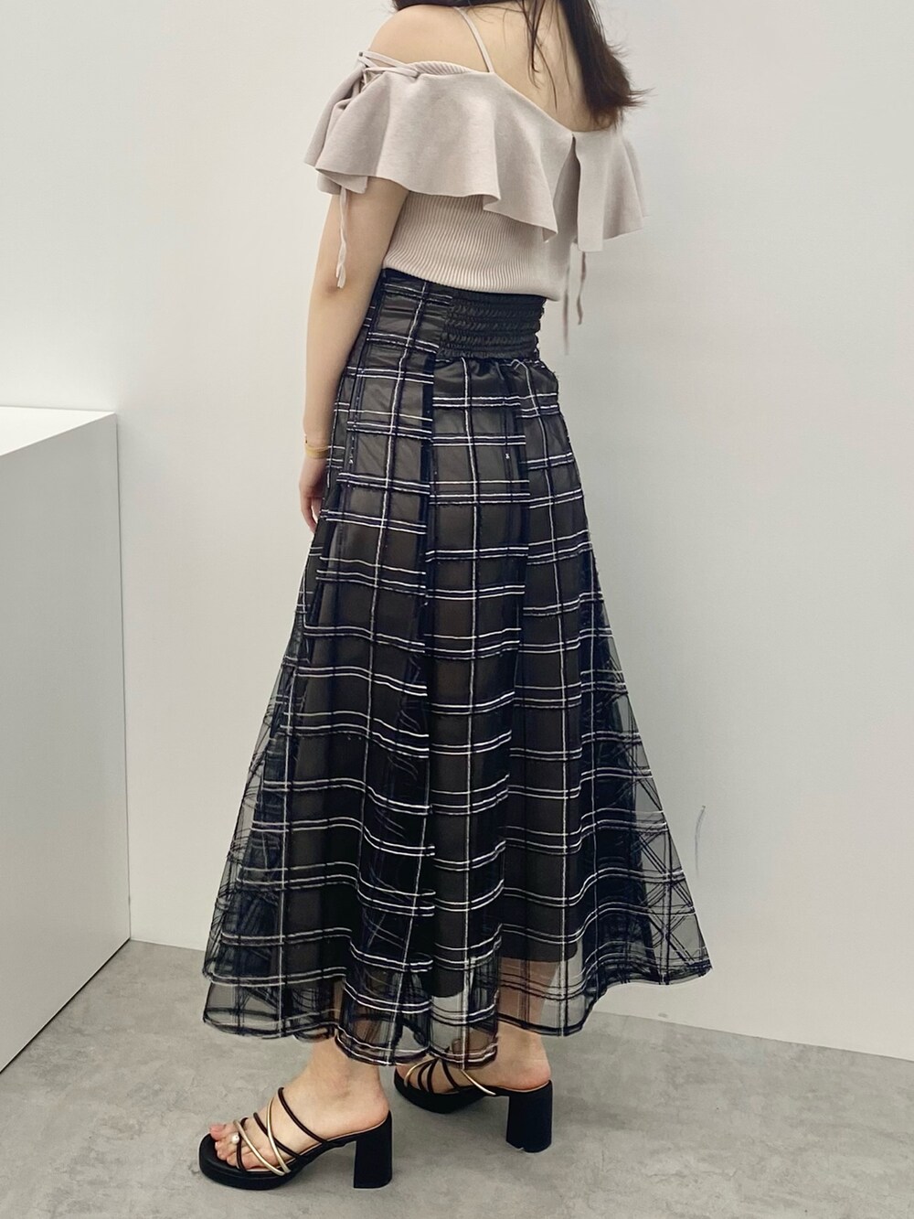 ブラック系のスカート、ホワイト系のサンダル、ピンク系のニット/セーターを着用したレディースの春コーディネートの3枚目の写真