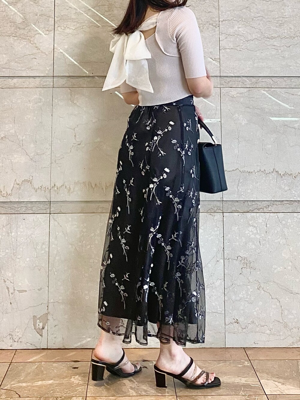 ブラック系のハンドバッグ、グレー系のスカート、ブラック系のサンダルを着用したレディースの春コーディネートの5枚目の写真