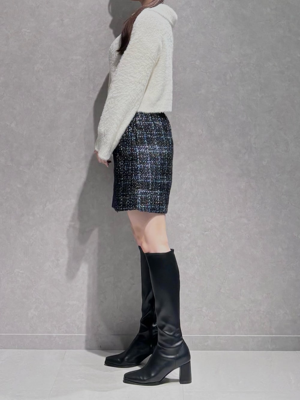 ブラック系のスカート、ブラック系のブーツ、ホワイト系のニット/セーターを着用したレディースの秋コーディネートの4枚目の写真