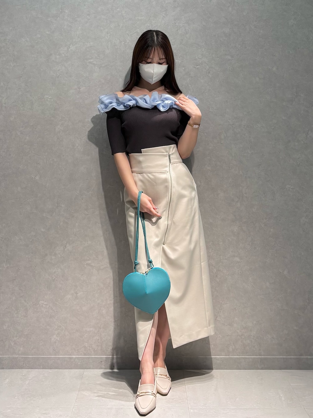 ホワイト系のスカート、グレー系のニット/セーター、グリーン系のショルダーバッグを着用したレディースの春コーディネートの2枚目の写真