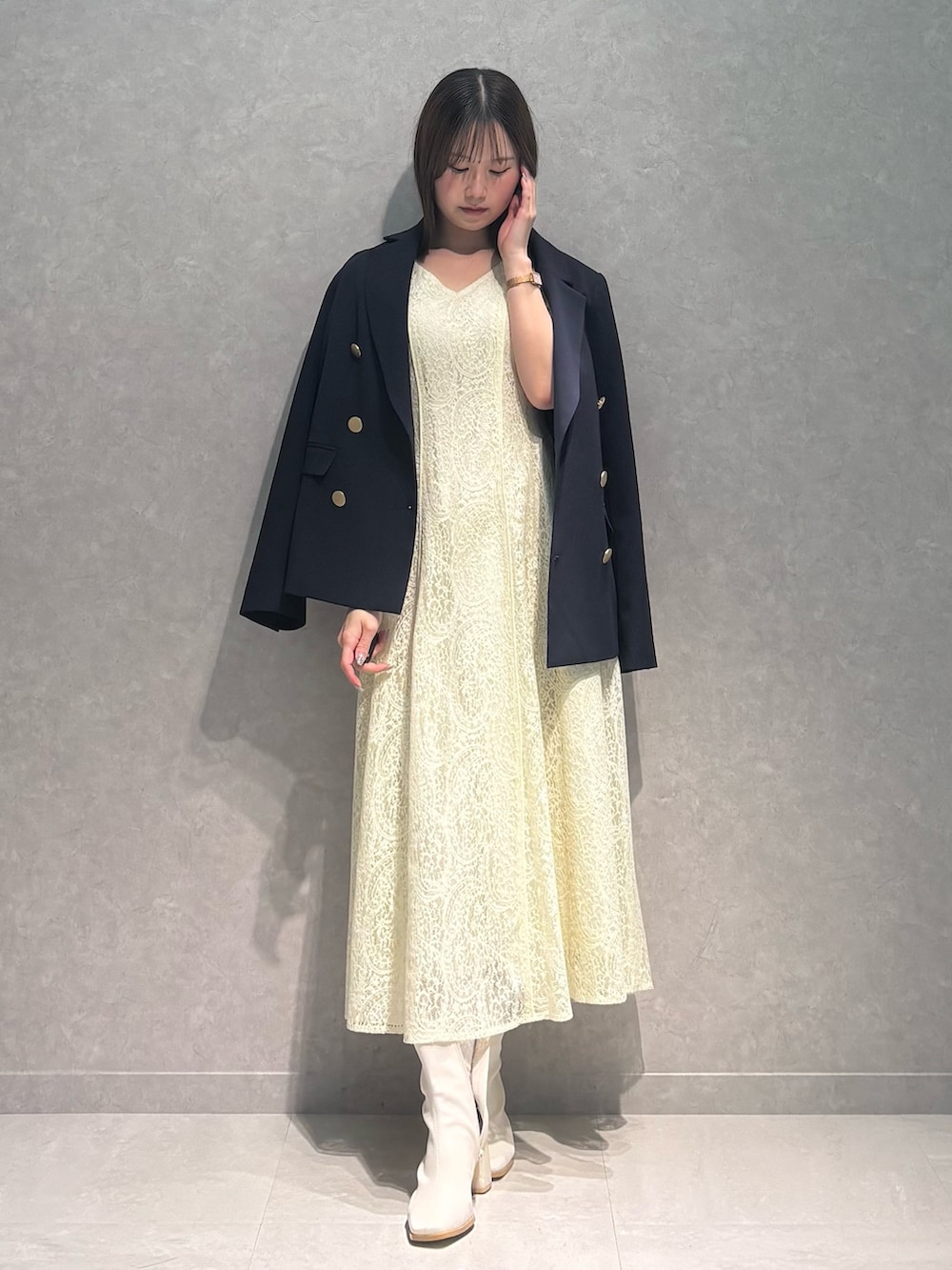 イエロー系のワンピース、ホワイト系のブーツ、ブルー系のテーラードジャケットを着用したレディースの春コーディネートの6枚目の写真