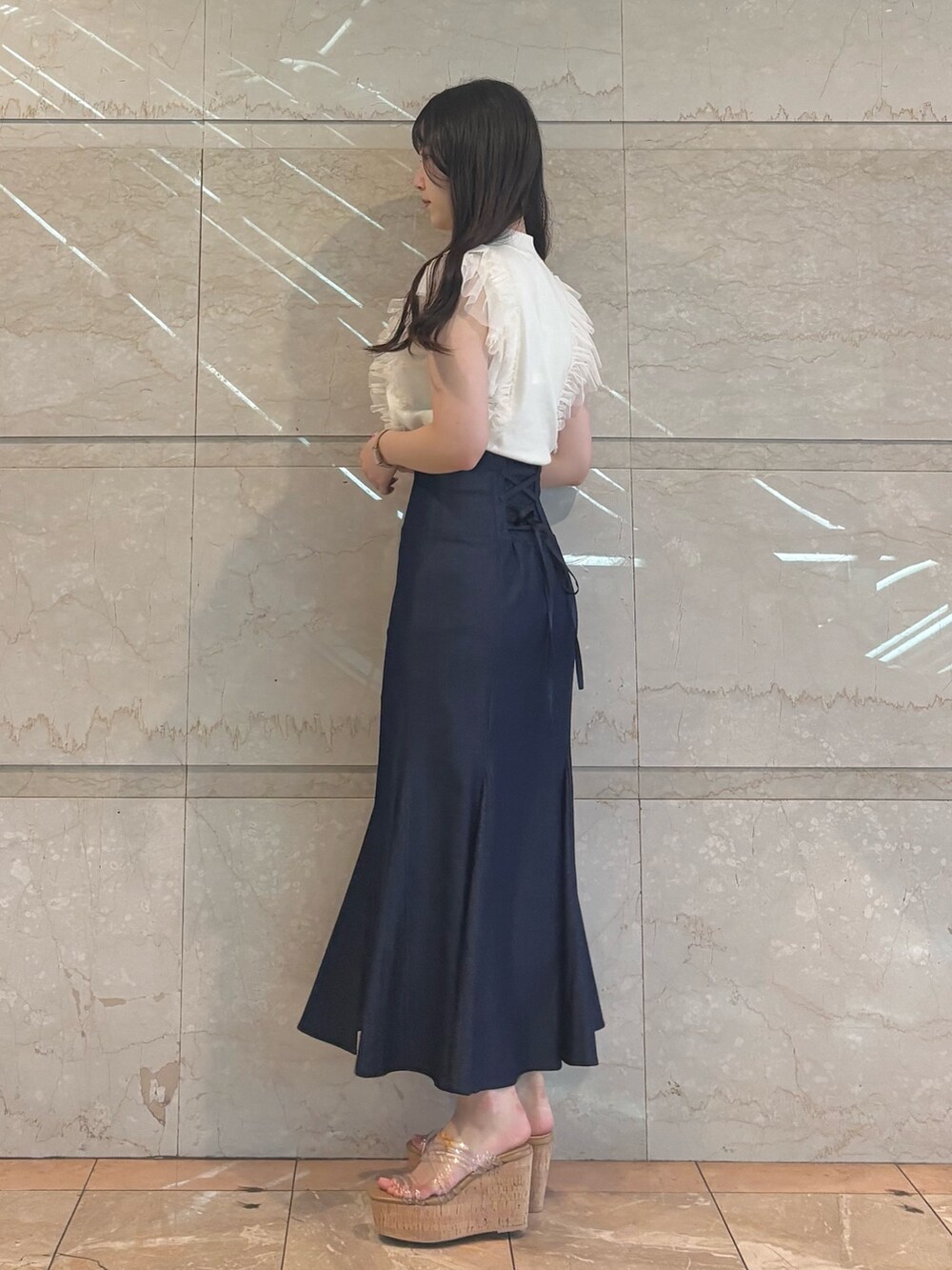 ブルー系のスカート、ホワイト系のニット/セーター、その他のサンダルを着用したレディースの春コーディネートの2枚目の写真