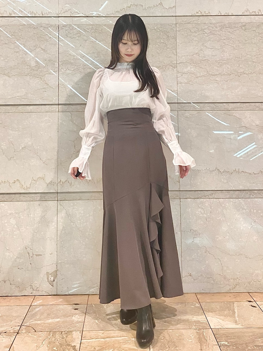 ブラウン系のスカート、ホワイト系のシャツ/ブラウス、ブラウン系のブーツを着用したレディースの冬コーディネートの2枚目の写真