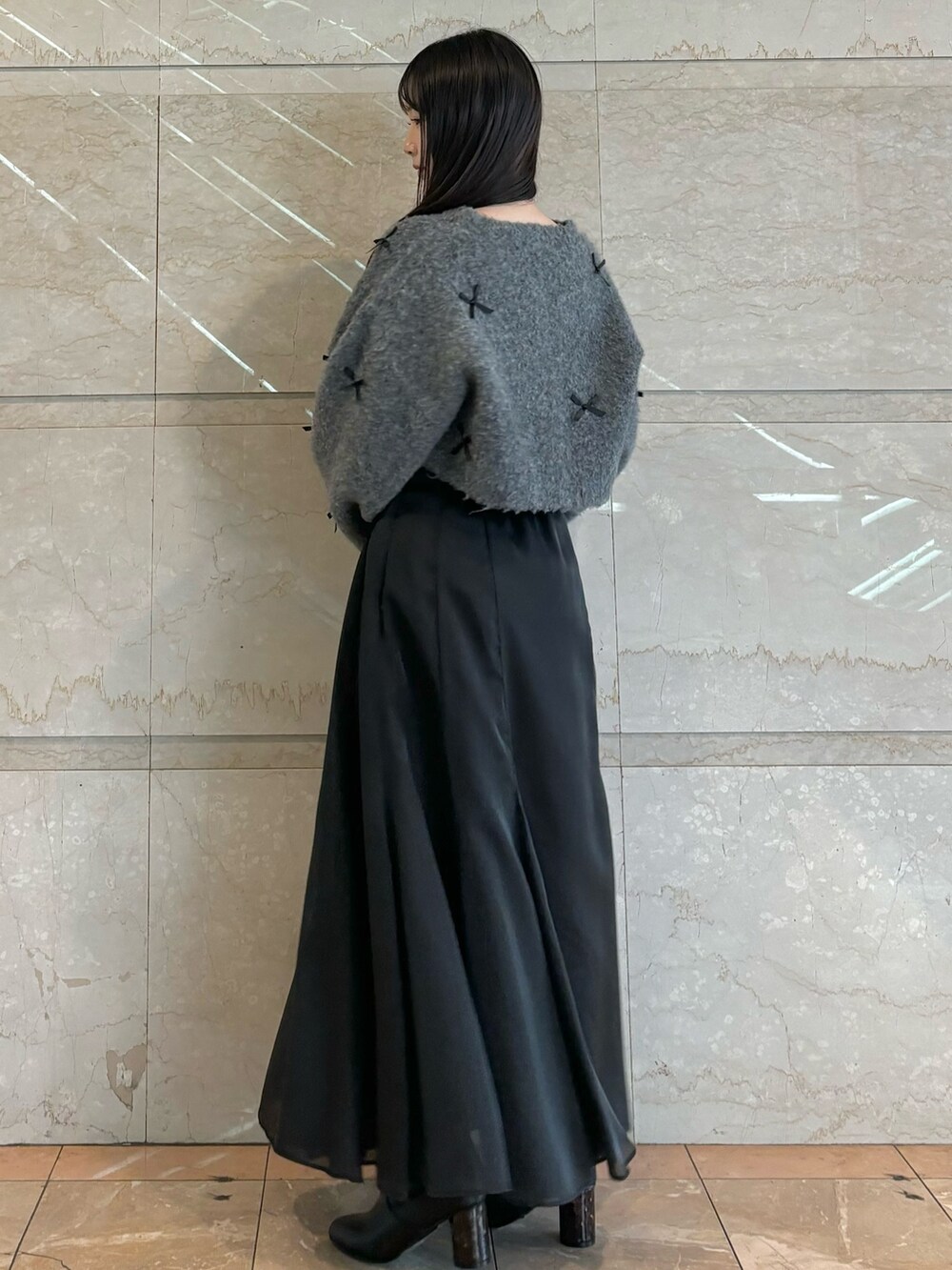 ブラック系のスカート、ブラック系のブーツ、グレー系のカーディガン/ボレロを着用したレディースの冬コーディネートの4枚目の写真