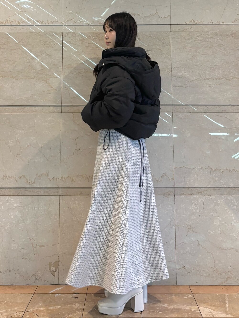 ホワイト系のスカート、ホワイト系のブーツ、ブラック系のダウンジャケット/コートを着用したレディースの冬コーディネートの2枚目の写真