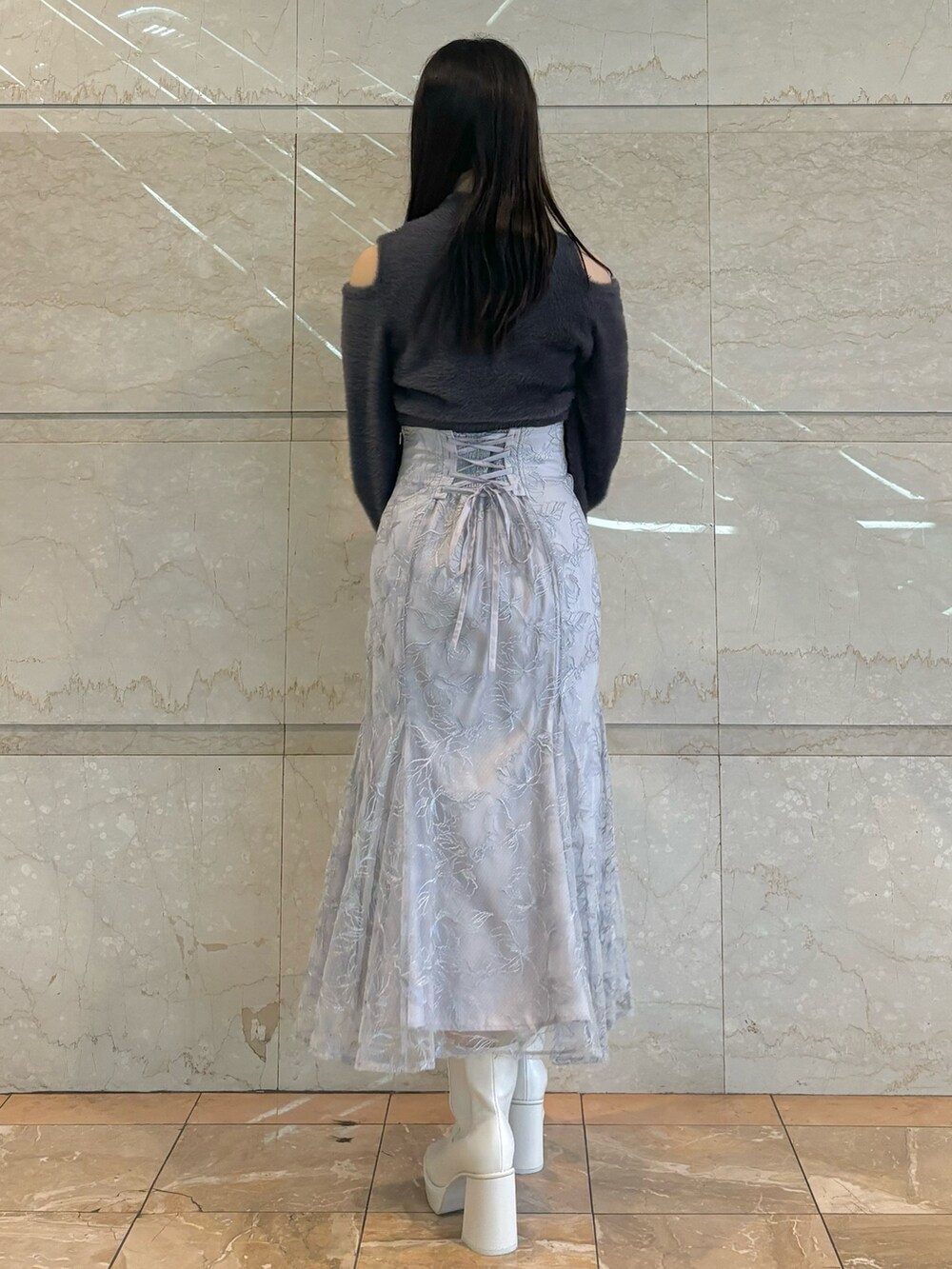 ブルー系のスカート、ホワイト系のブーツ、グレー系のニット/セーターを着用したレディースの秋コーディネートの3枚目の写真