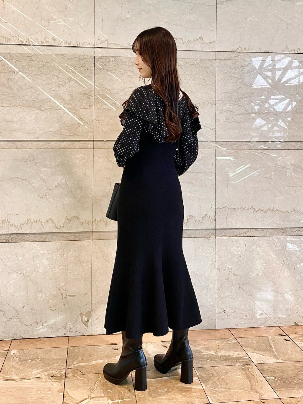 ブラック系のワンピース、ブラック系のブーツ、ブラック系のハンドバッグを着用したレディースの秋コーディネートの2枚目の写真