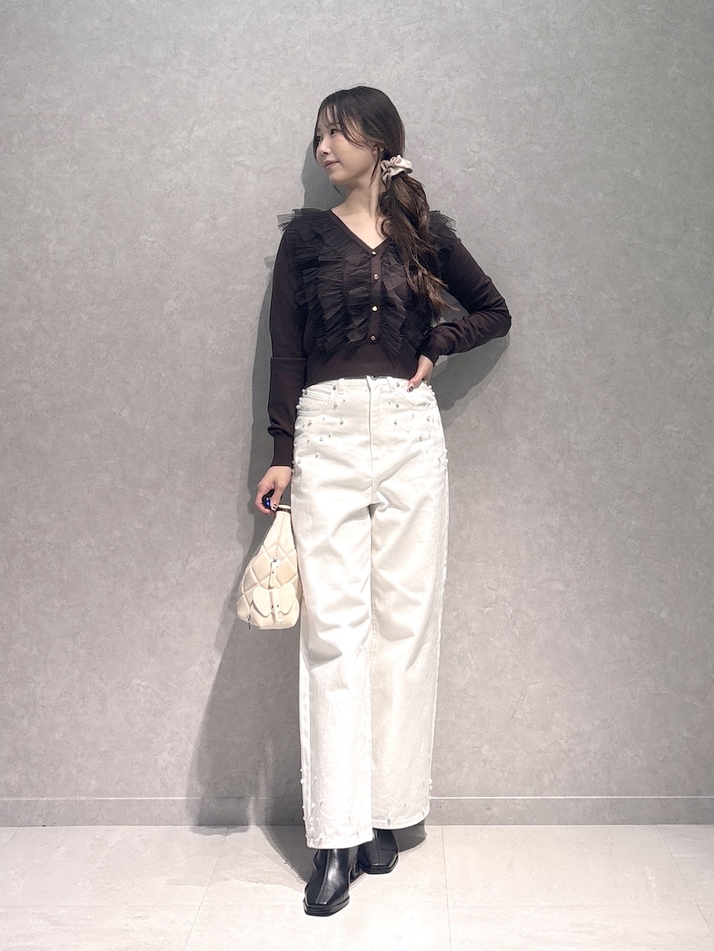 ホワイト系のデニムパンツ、ブラウン系のニット/セーター、ホワイト系のハンドバッグを着用したレディースの秋コーディネートの2枚目の写真