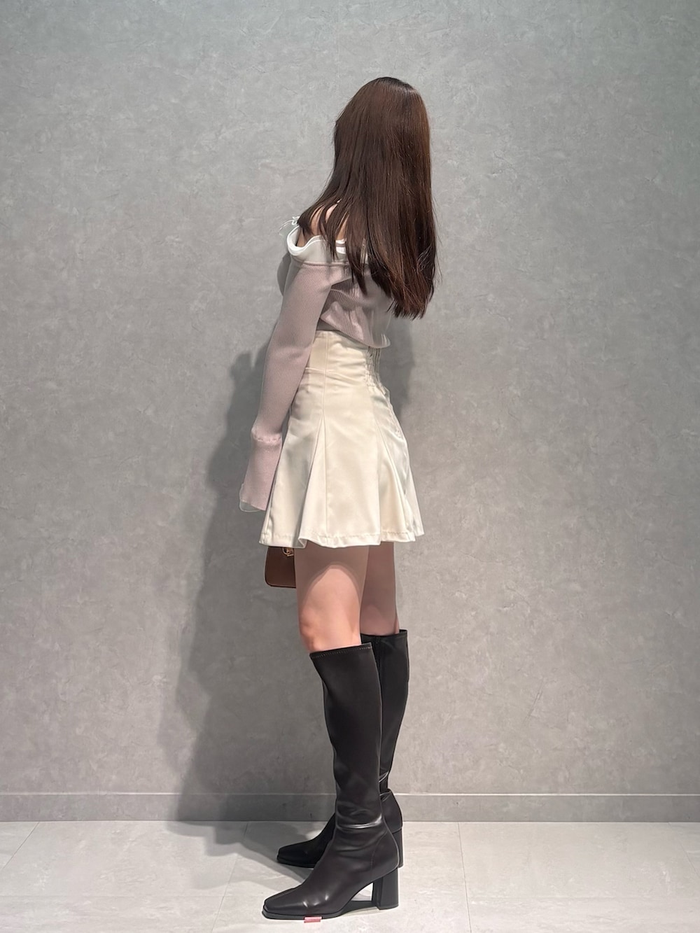 ベージュ系のニット/セーター、ホワイト系のスカート、ブラウン系のハンドバッグを着用したレディースの冬コーディネートの3枚目の写真