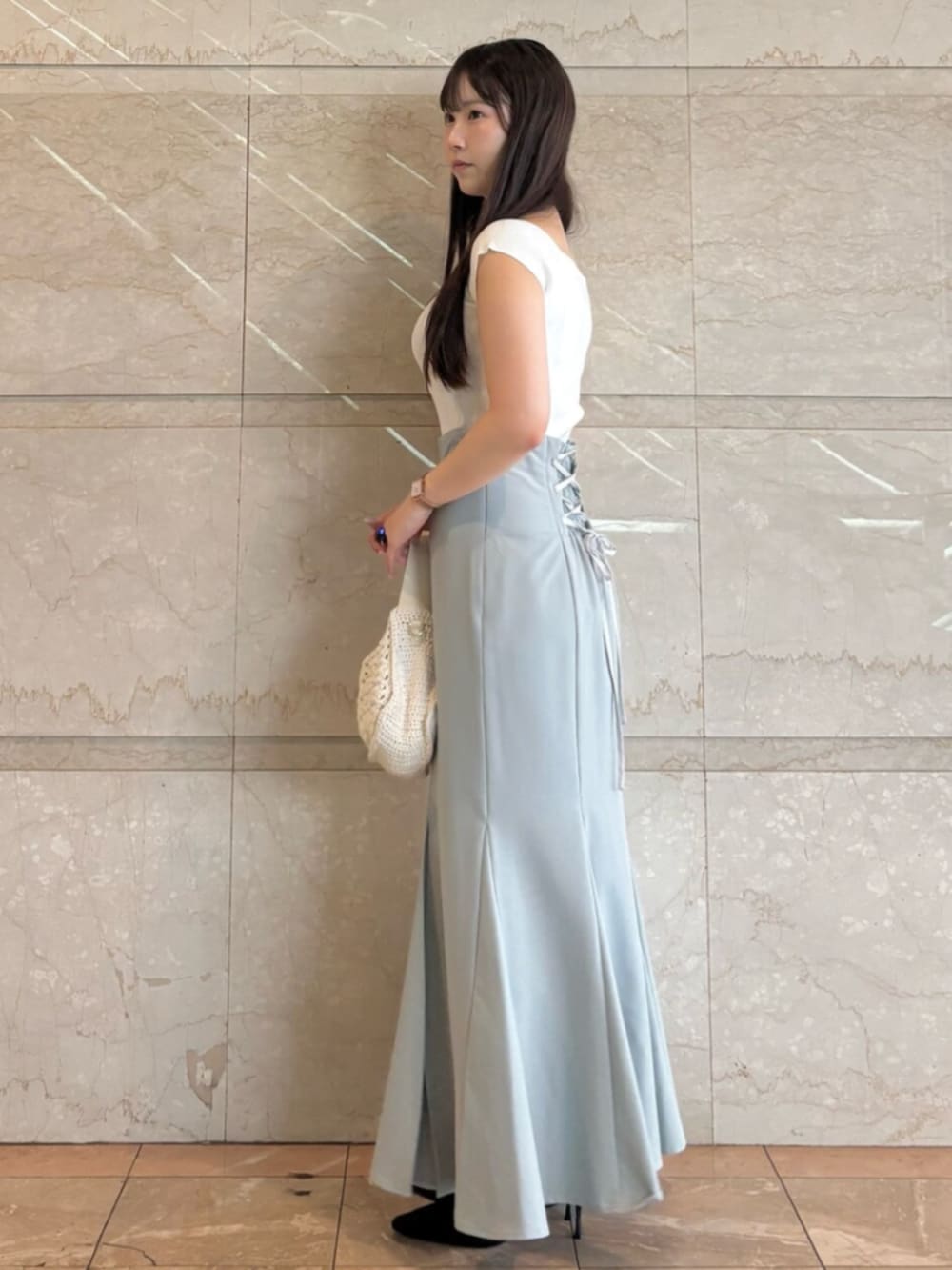 ブラック系のパンプス、ブルー系のスカート、ホワイト系のニット/セーターを着用したレディースの夏コーディネートの3枚目の写真