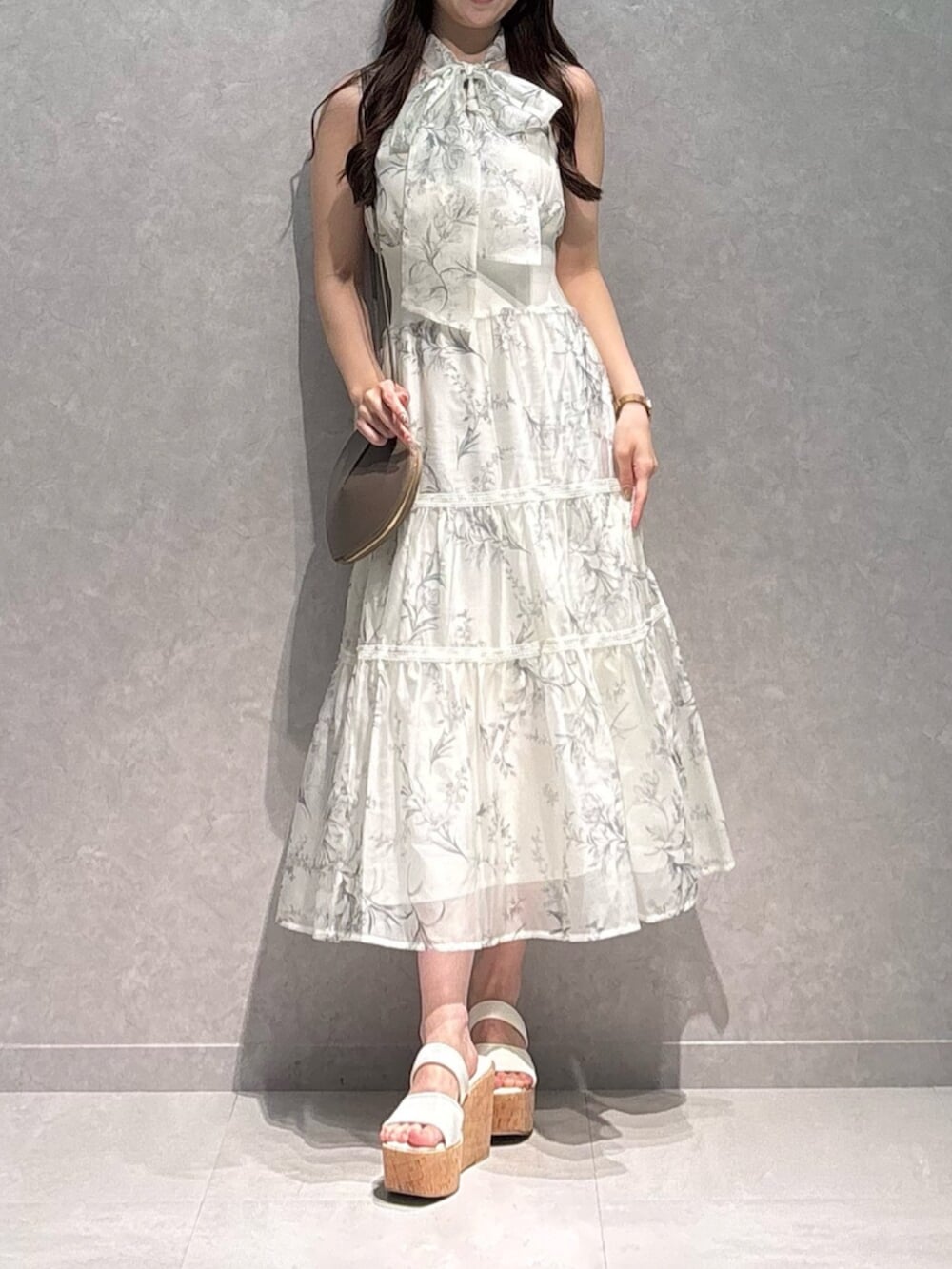 ベージュ系のショルダーバッグ、ホワイト系のサンダル、ホワイト系のワンピースを着用したレディースの夏コーディネートの2枚目の写真