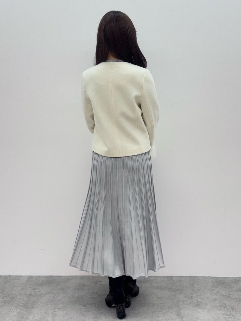 ブラック系のブーツ、ホワイト系のその他アウター、グレー系のワンピースを着用したレディースの冬コーディネートの5枚目の写真