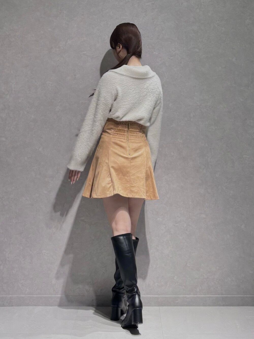 イエロー系のスカート、ホワイト系のニット/セーター、ブラック系のブーツを着用したレディースの秋コーディネートの5枚目の写真