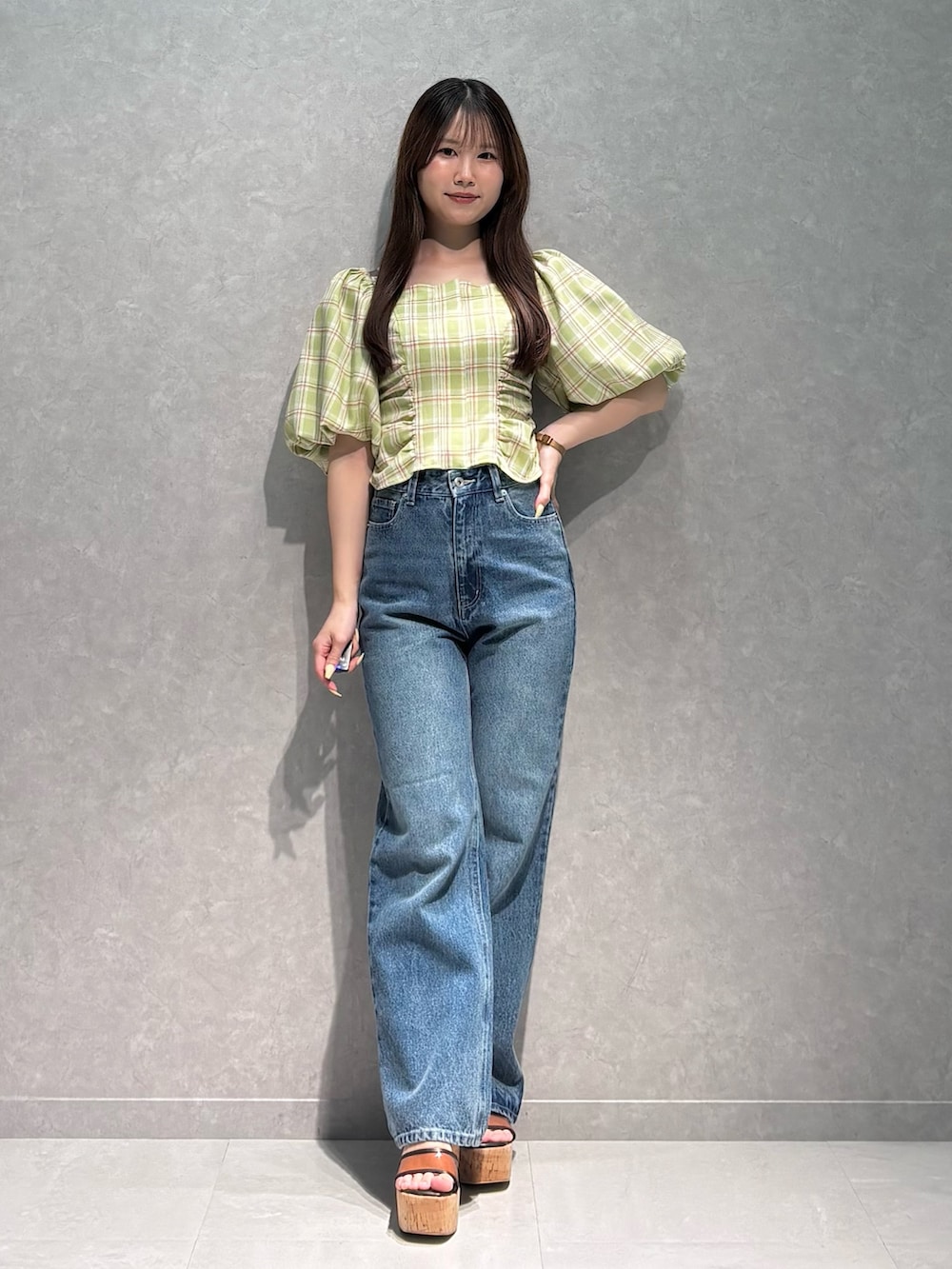 ブルー系のデニムパンツ、ブラウン系のサンダル、グリーン系のシャツ/ブラウスを着用したレディースの春コーディネートの2枚目の写真