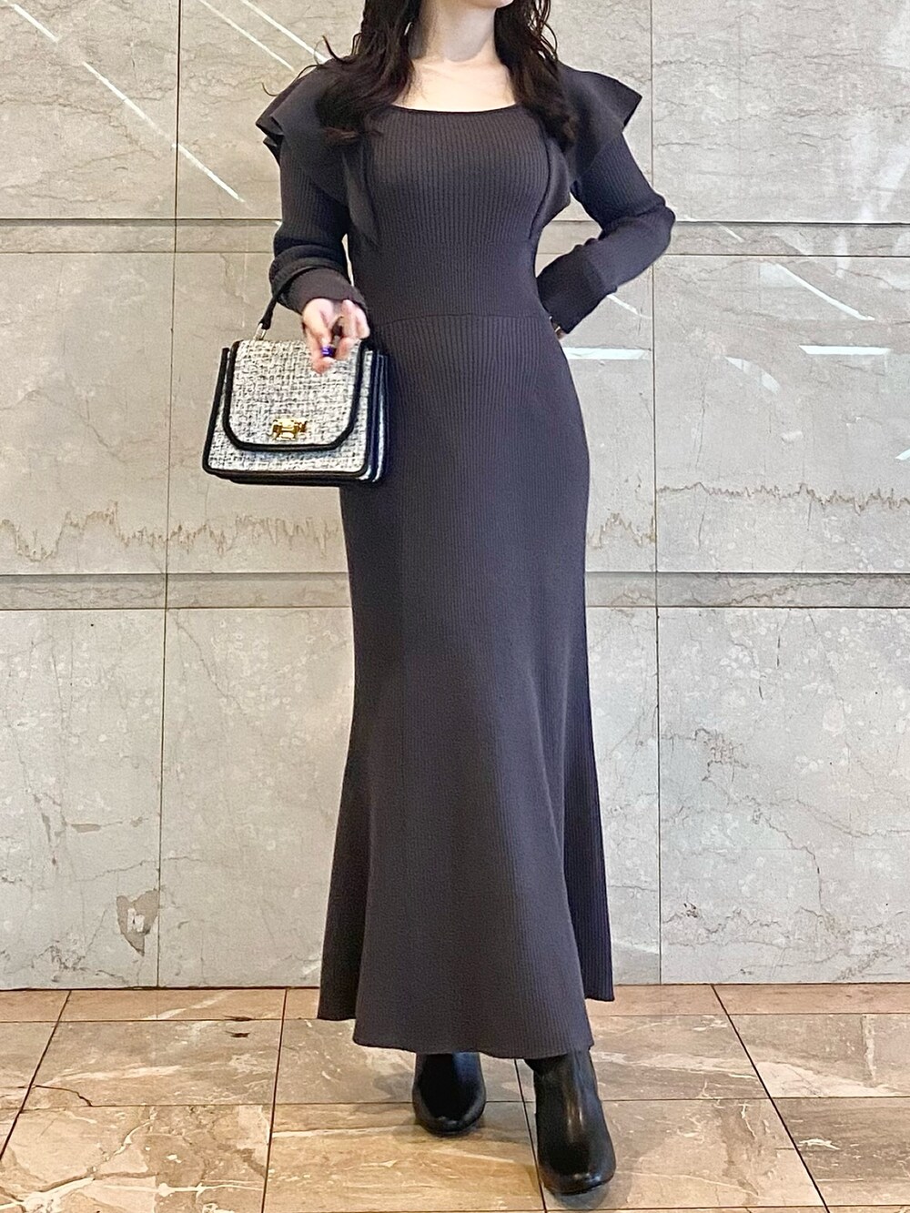 グレー系のワンピース、ブラック系のブーツ、ブラック系のハンドバッグを着用したレディースの冬コーディネートの2枚目の写真