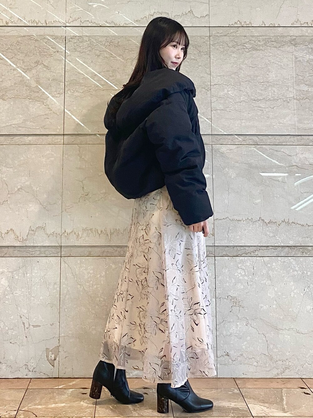 ベージュ系のスカート、グレー系のニット/セーター、ブラック系のダウンジャケット/コートを着用したレディースの冬コーディネートの5枚目の写真