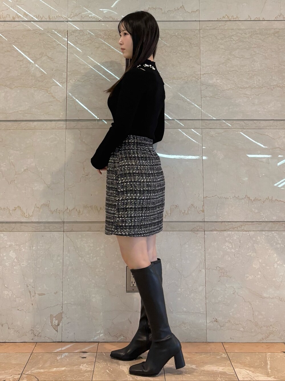 ブラック系のスカート、ブラック系のニット/セーター、ブラウン系のブーツを着用したレディースの冬コーディネートの4枚目の写真